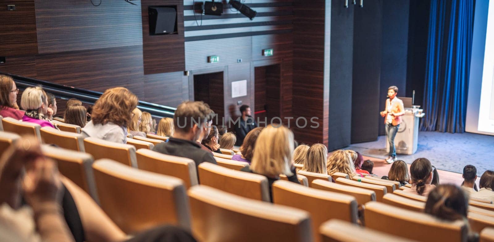 Speaker giving a talk in conference hall at business event. Rear view of unrecognizable people in audience at the conference hall. Business and entrepreneurship concept