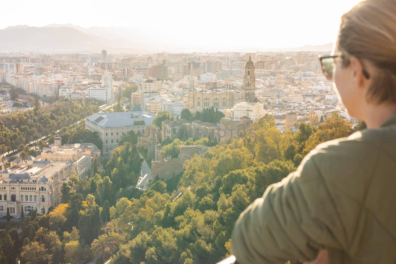 Bolnde female touris enjoying amazing panoramic aerial view of Malaga city historic center, Coste del Sol, Andalucia, Spain.
