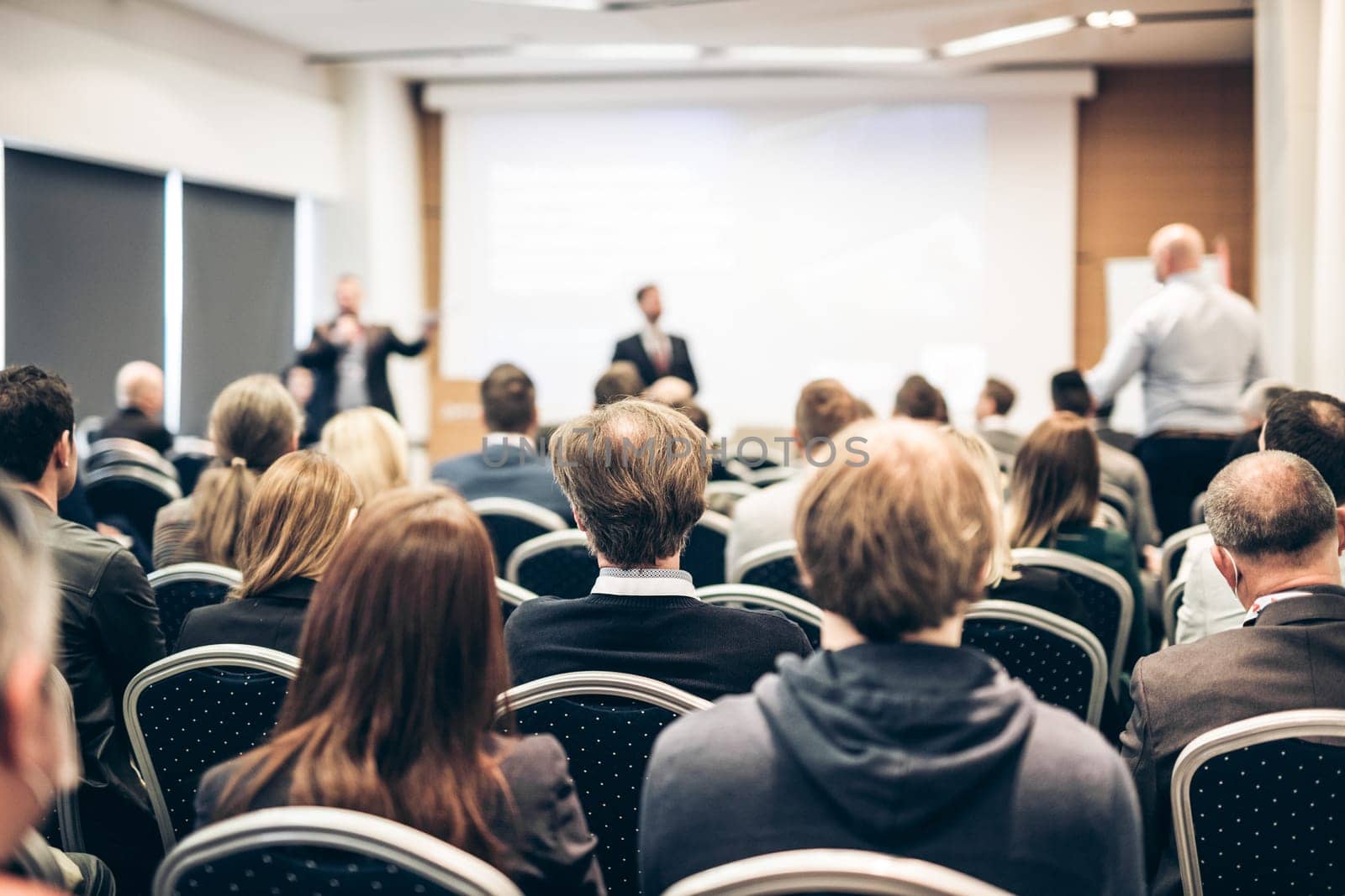I have a question. Group of business people sitting at the chairs in conference hall. Businessman standing up asking a question. Conference and Presentation. Business and Entrepreneurship.
