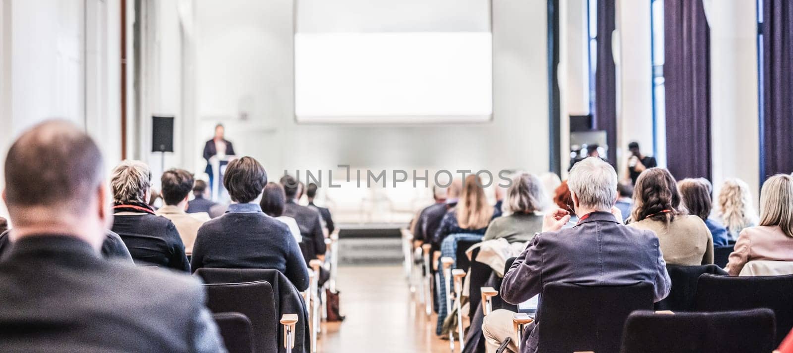 Speaker giving a talk in conference hall at business event. Rear view of unrecognizable people in audience at the conference hall. Business and entrepreneurship concept