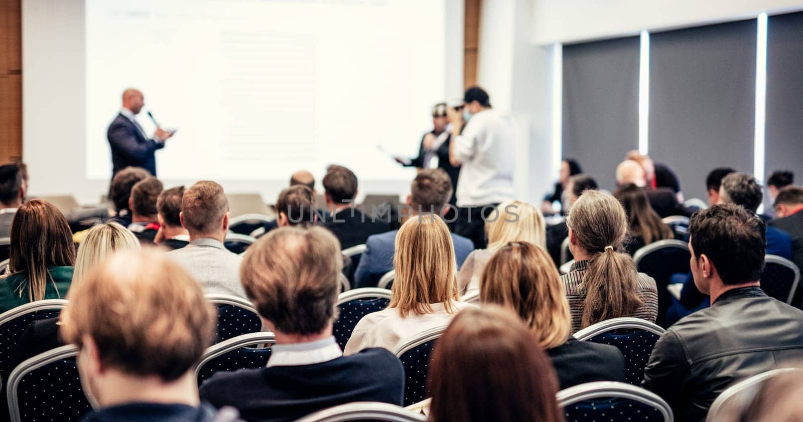I have a question. Group of business people sitting at the chairs in conference hall. Businessman standing up asking a question. Conference and Presentation. Business and Entrepreneurship.