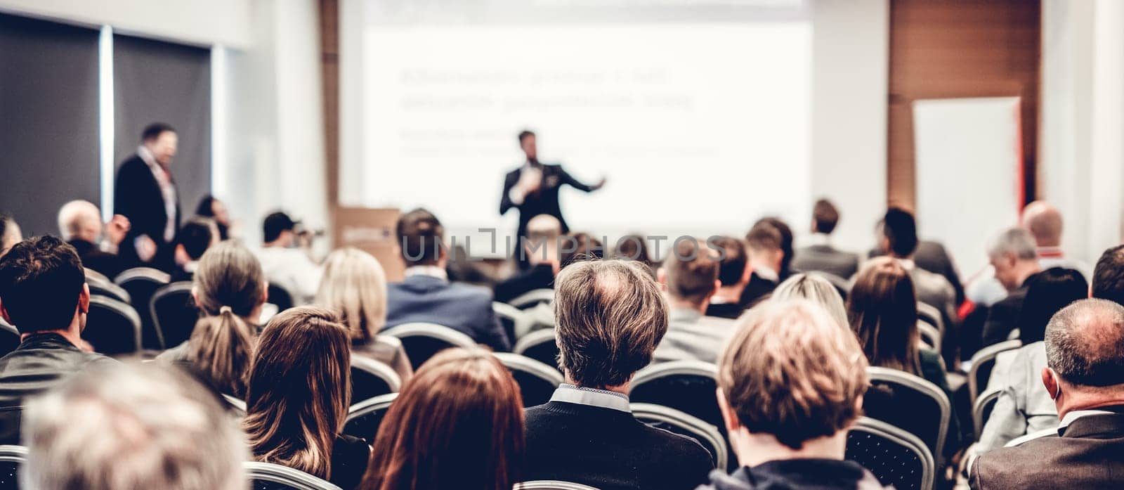 Speaker giving a talk in conference hall at business event. Rear view of unrecognizable people in audience at the conference hall. Business and entrepreneurship concept