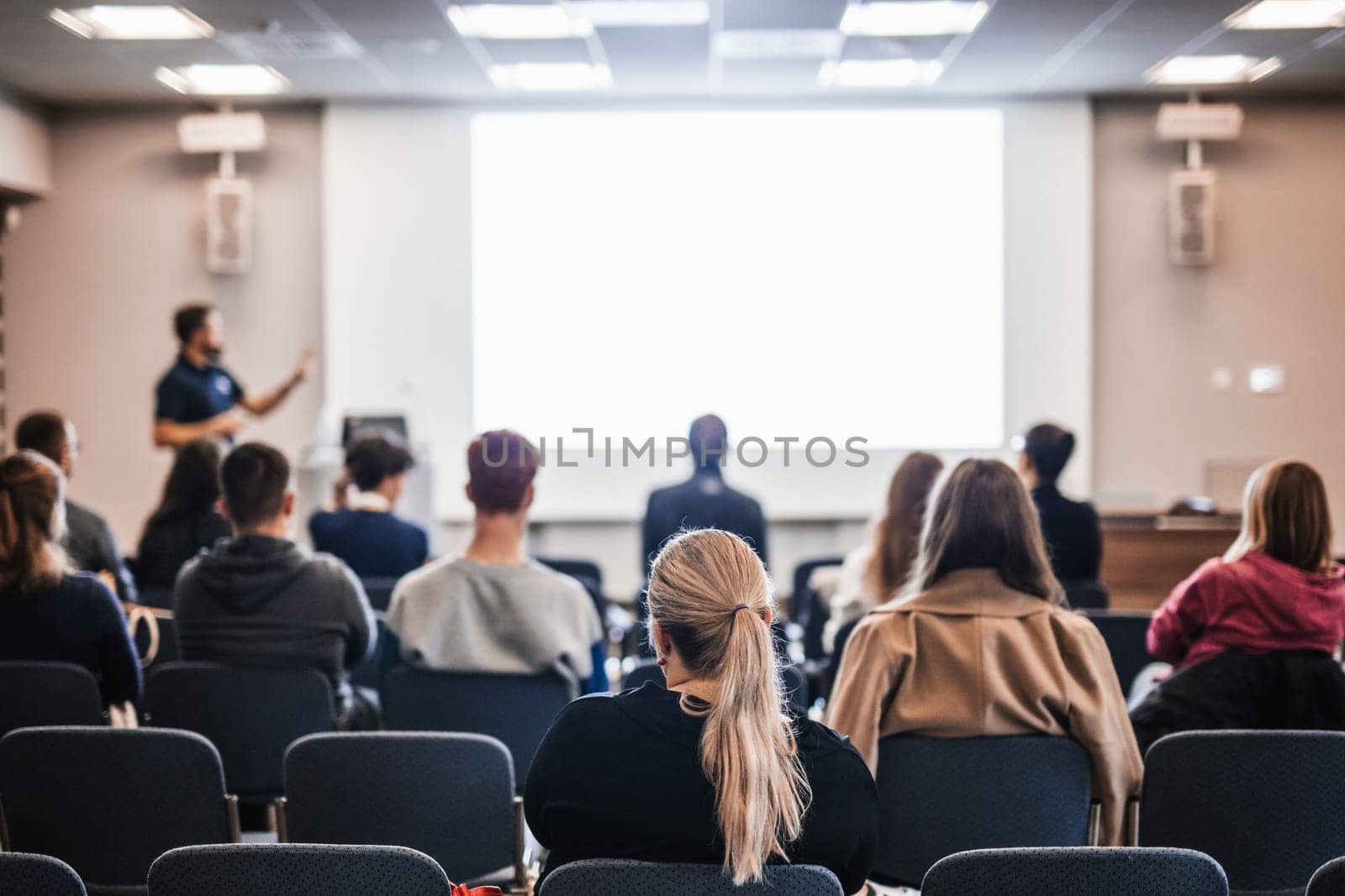 Speaker giving a talk in conference hall at business event. Rear view of unrecognizable people in audience at the conference hall. Business and entrepreneurship concept