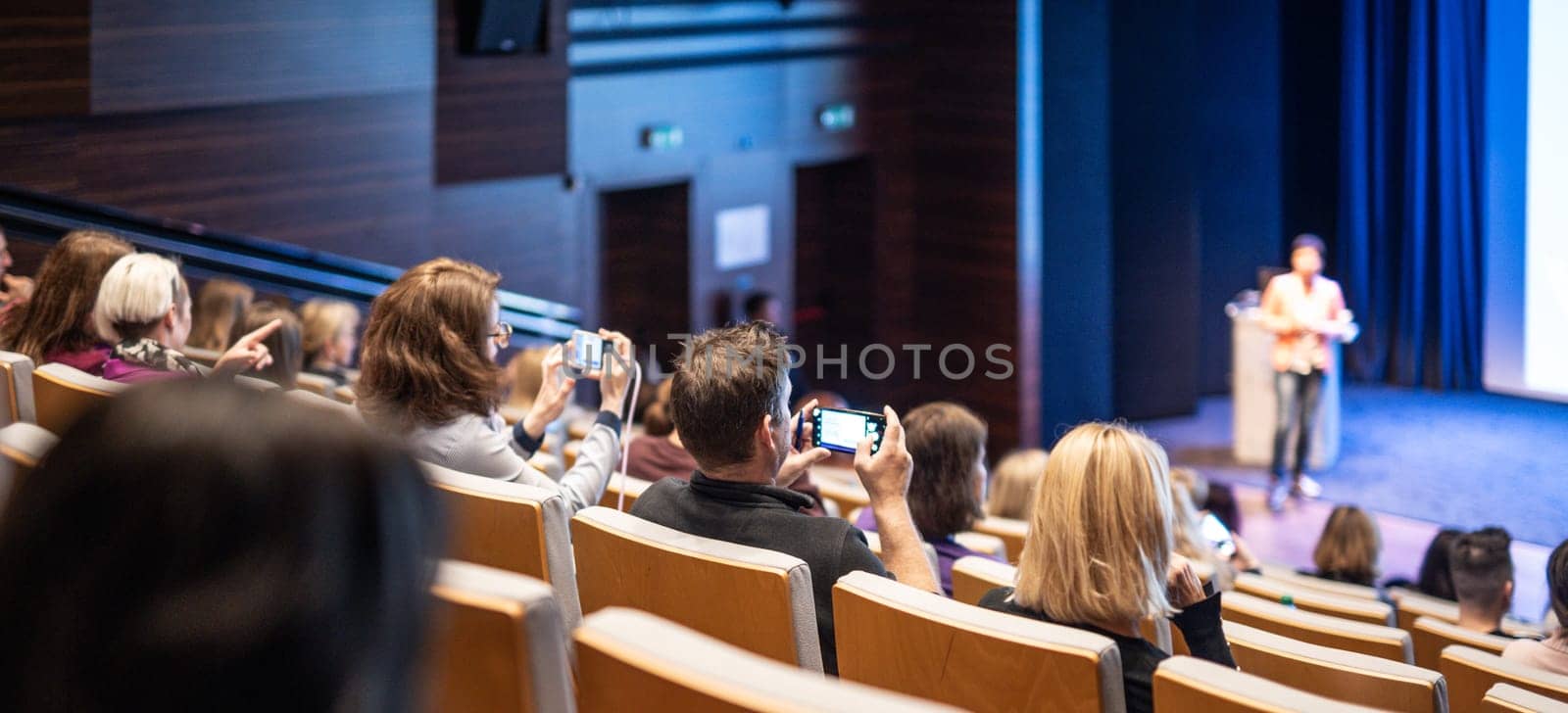 Speaker giving a talk in conference hall at business event. Rear view of unrecognizable people in audience at the conference hall. Business and entrepreneurship concept
