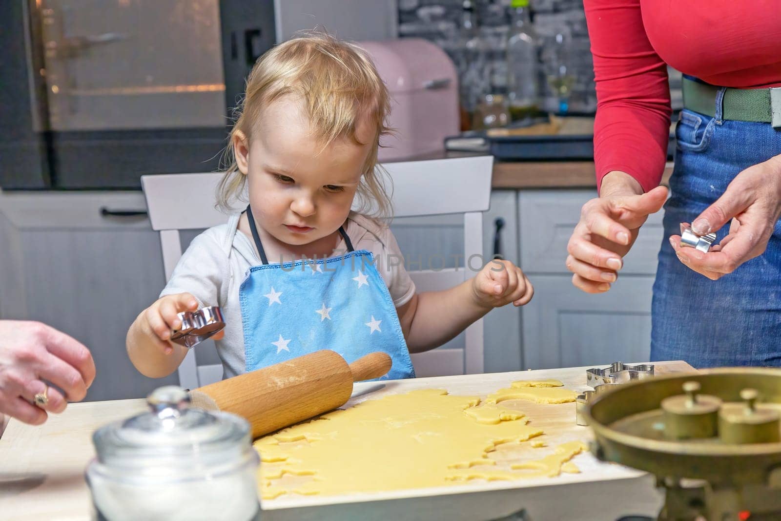 Adorable little child boy cuts out cookies from the dough in domestic kitchen.  Horizontally.