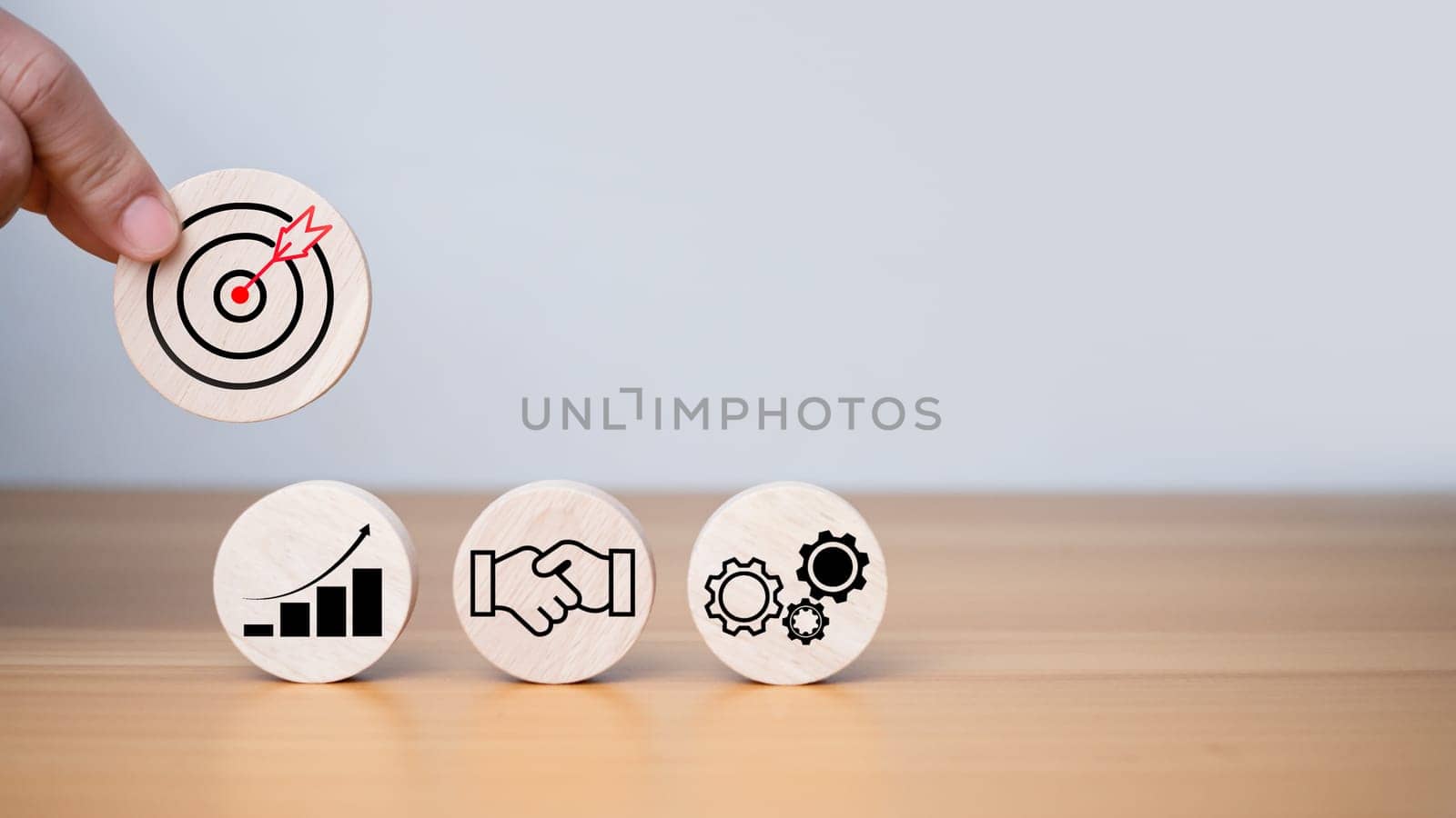 Businessman's hands hold a circular wooden board with printed target icons, business goals and objectives concept, business competition.