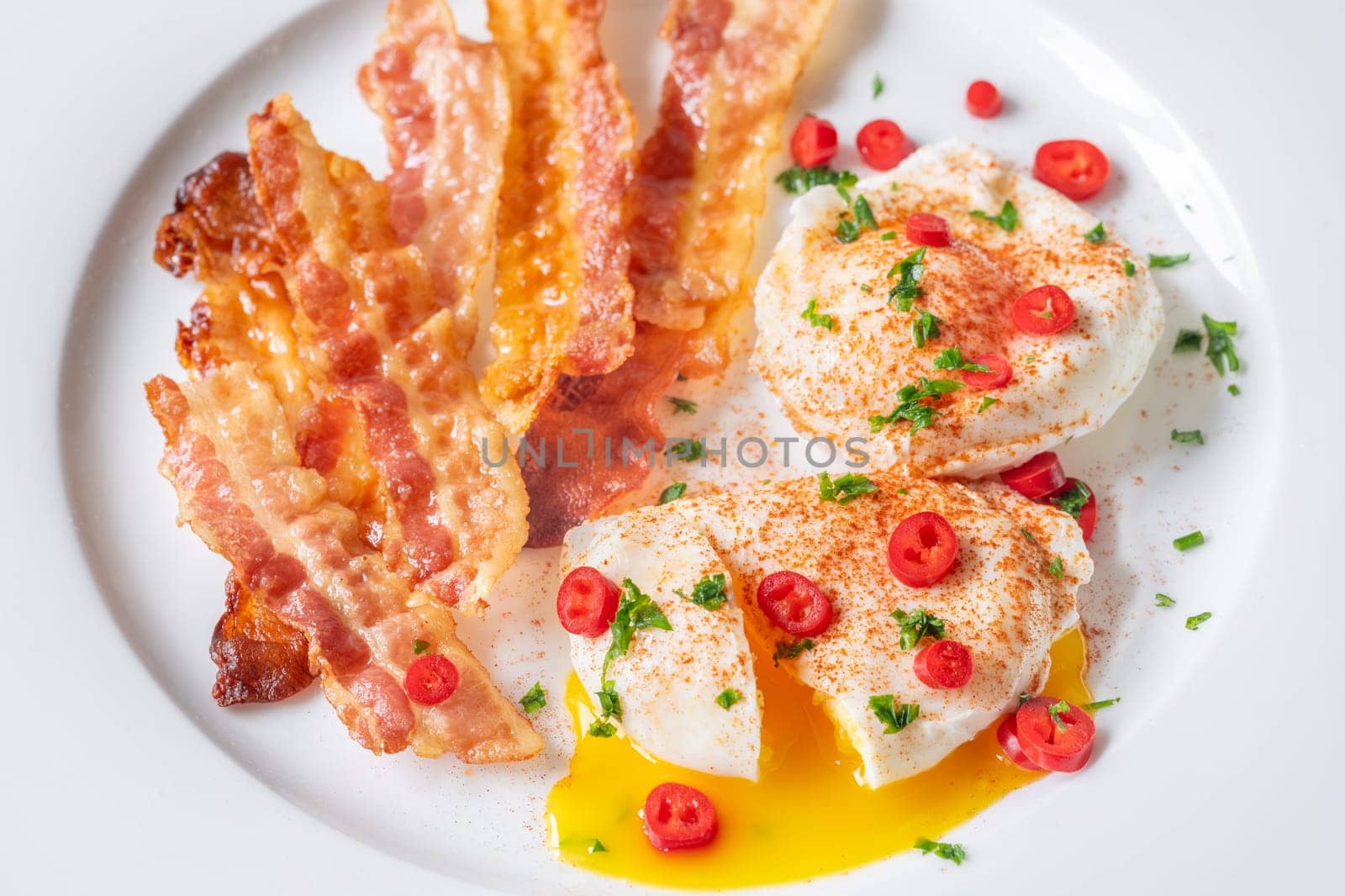 Portion of chili poached eggs with crispy bacon