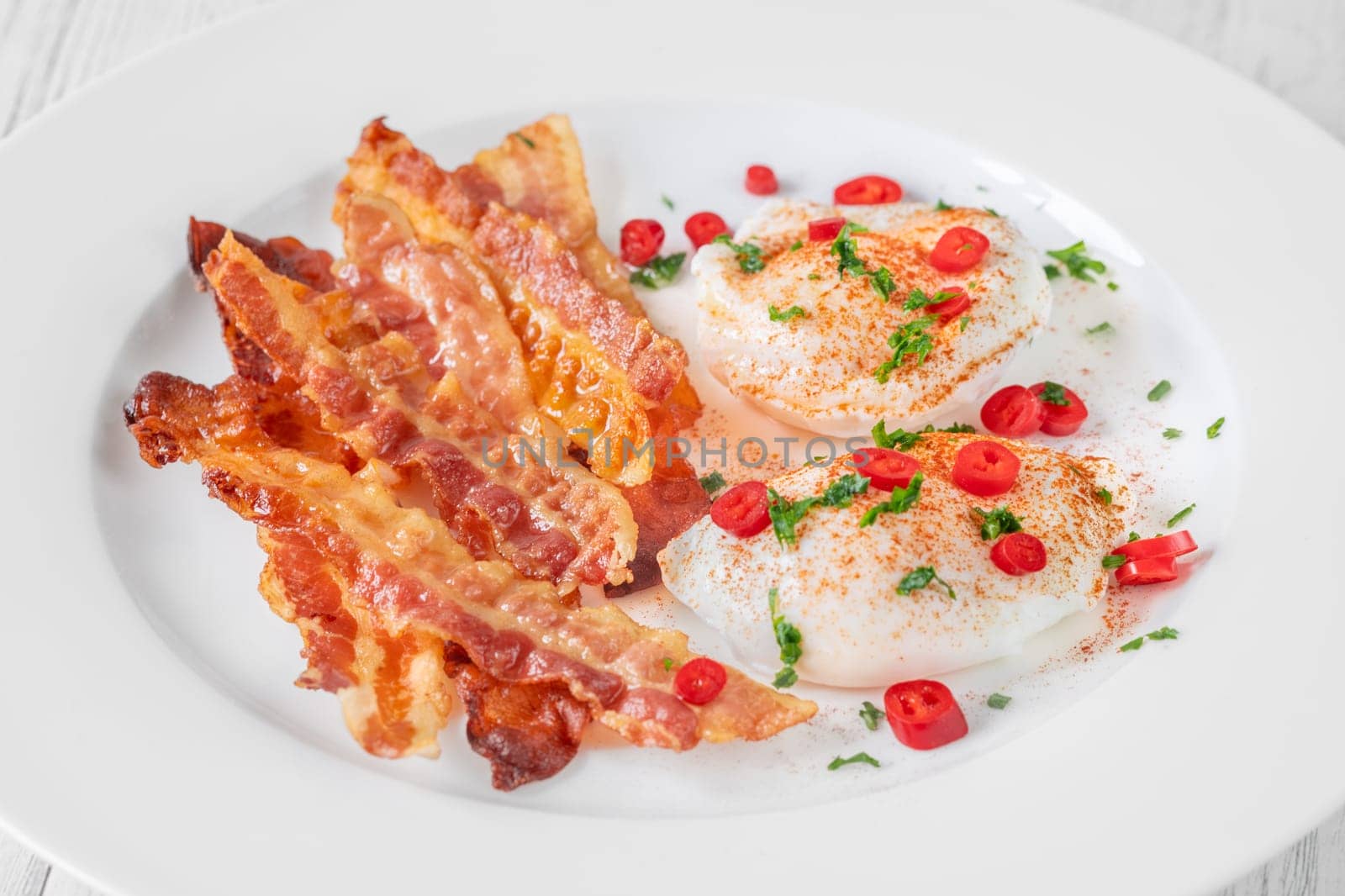 Portion of chili poached eggs with crispy bacon