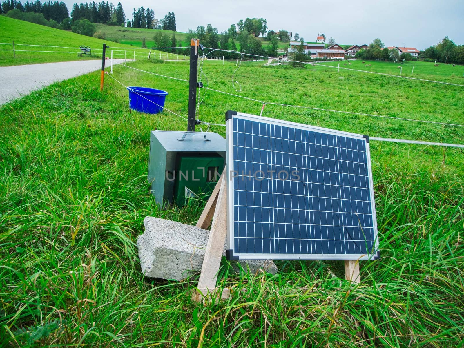 Small mobile photovoltaic system on an electric fence in Bavaria in summer under an overcast sky.