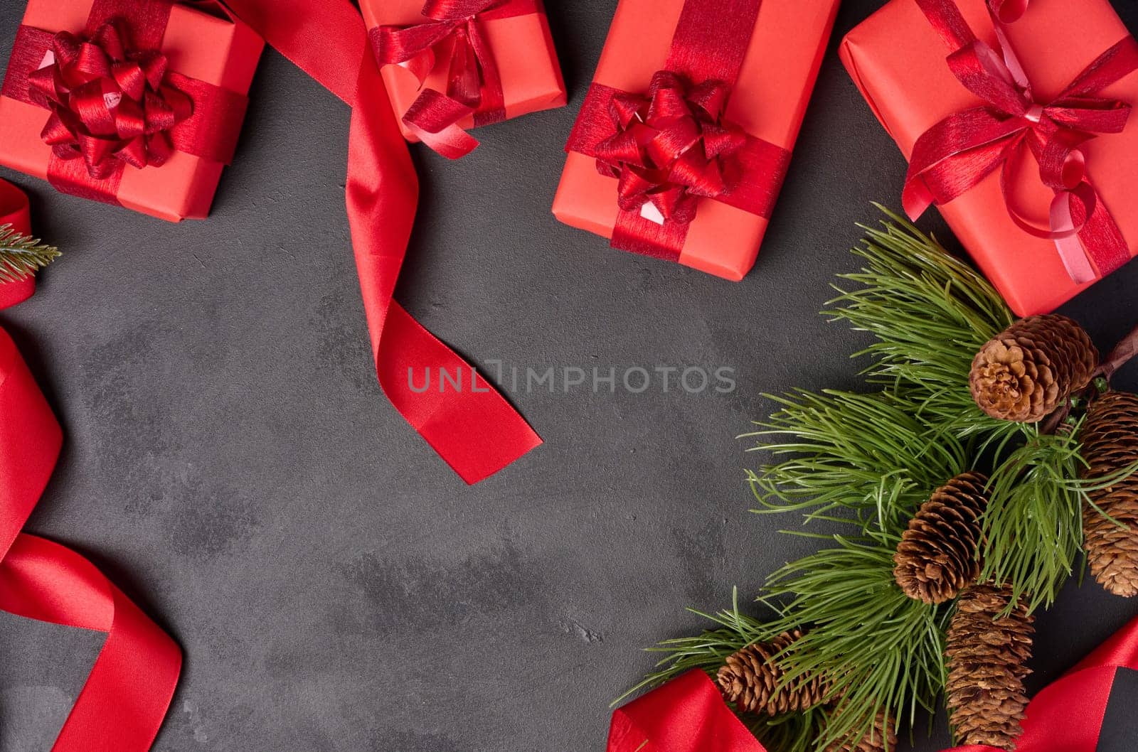 Christmas gifts and fir branch with pine cones on a black background, top view