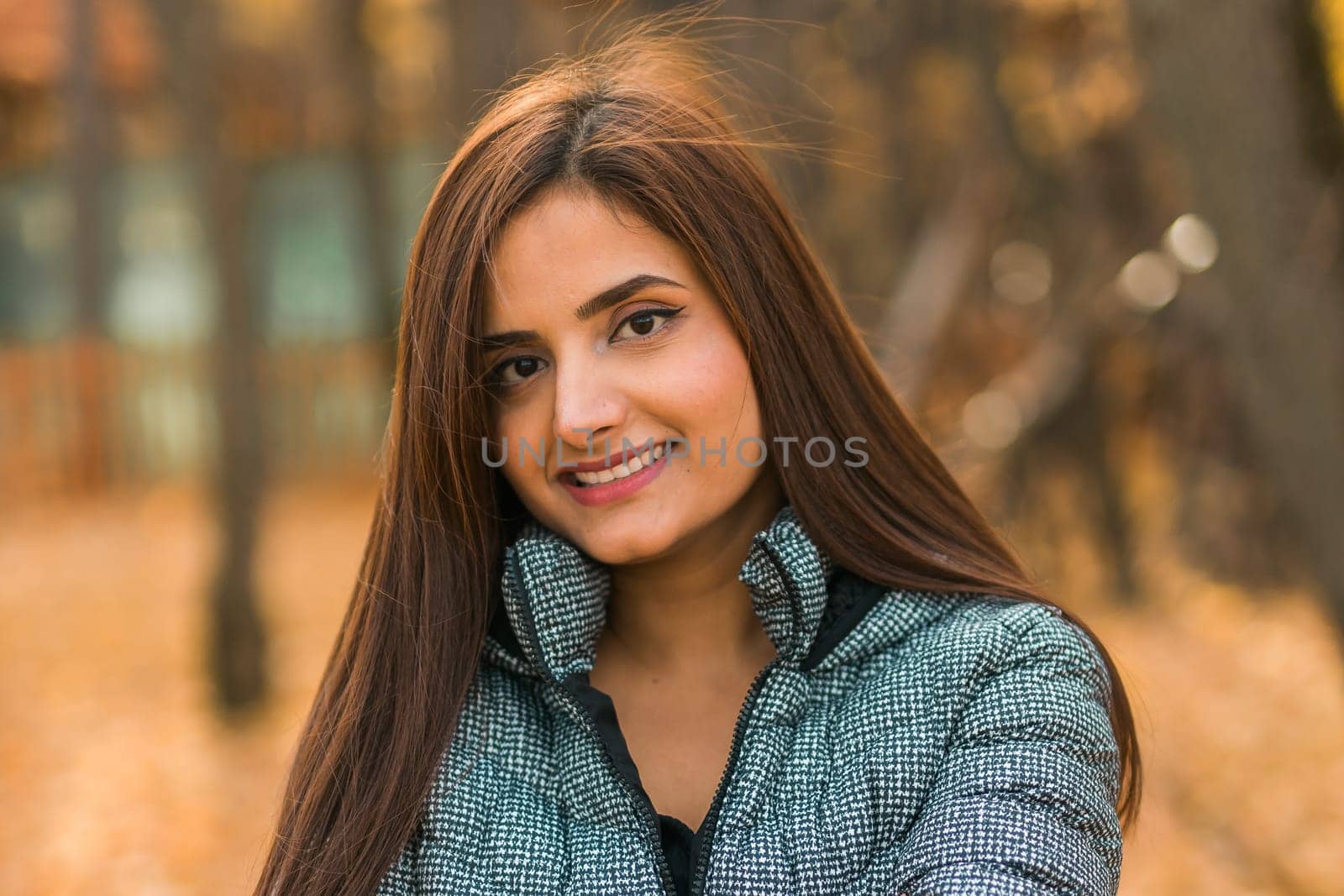 Close up portrait of pretty indian young woman enjoying warm autumn sunny day vacation outdoors. Generation z and gen z concept. Fall Season.