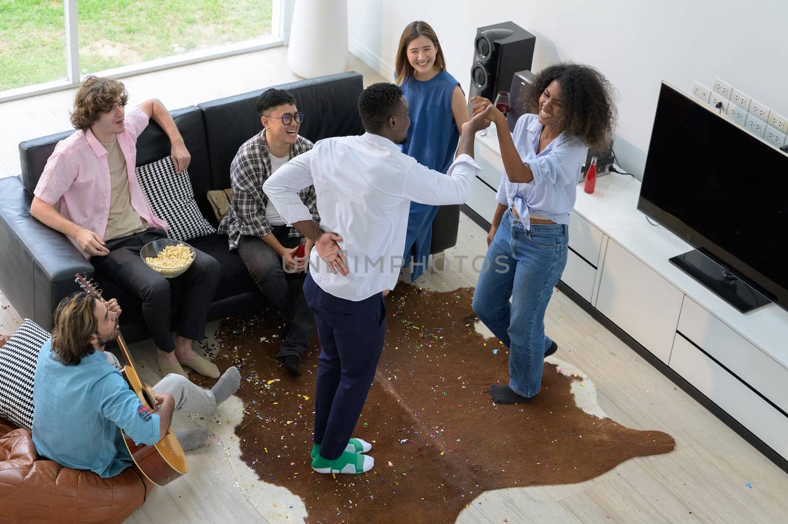 Diversity group of friends having party together at home. Happiness young people having fun dancing, playing guitar and singing in the living room. Top view image. Youth lifestyle concept
