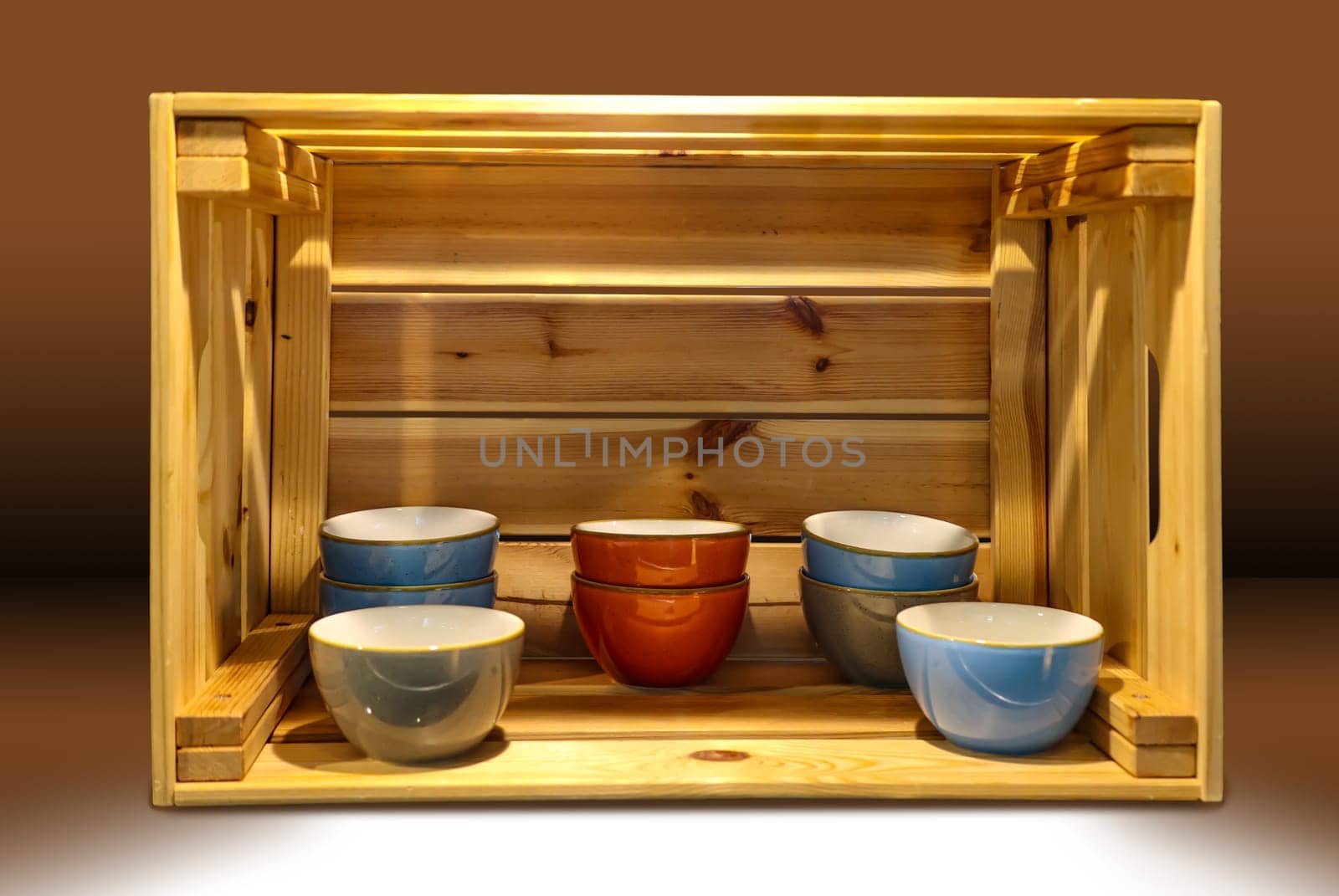 Several ceramic bowls stand very decoratively in a wooden box.