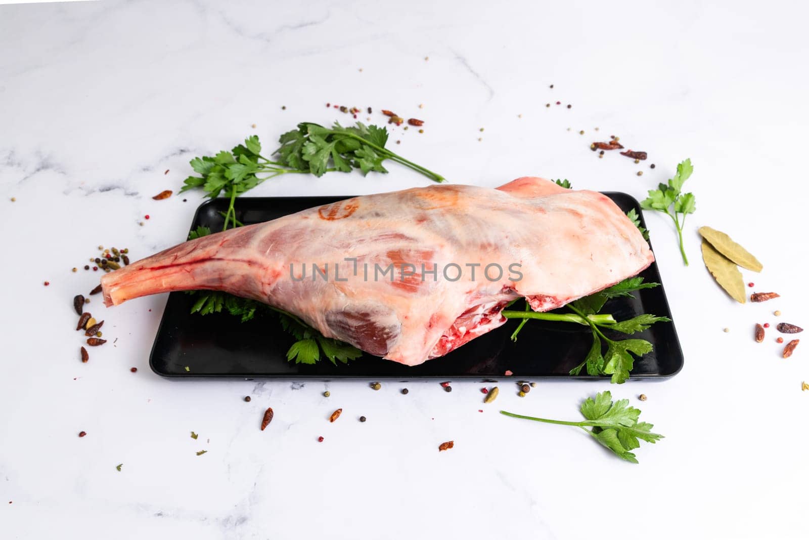 Raw lamb shoulder ready for cooking with garlic, rosemary. Black background. Top view