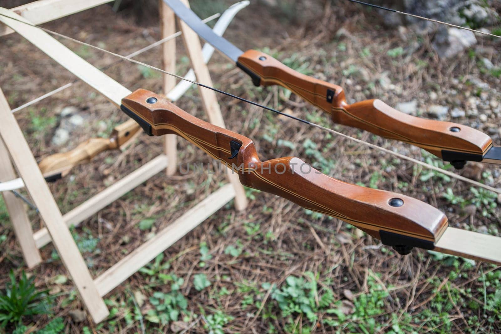 Wooden bows displayed over folding sawhorses. Forest background