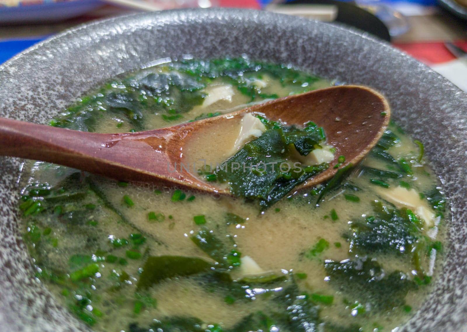 Miso soup with seaweed and tofu. Wooden spoon on grey bowl