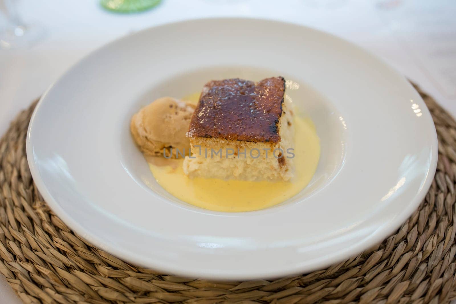 Wet brioche with scoop of vanilla ice cream. Plate served over rattan mat