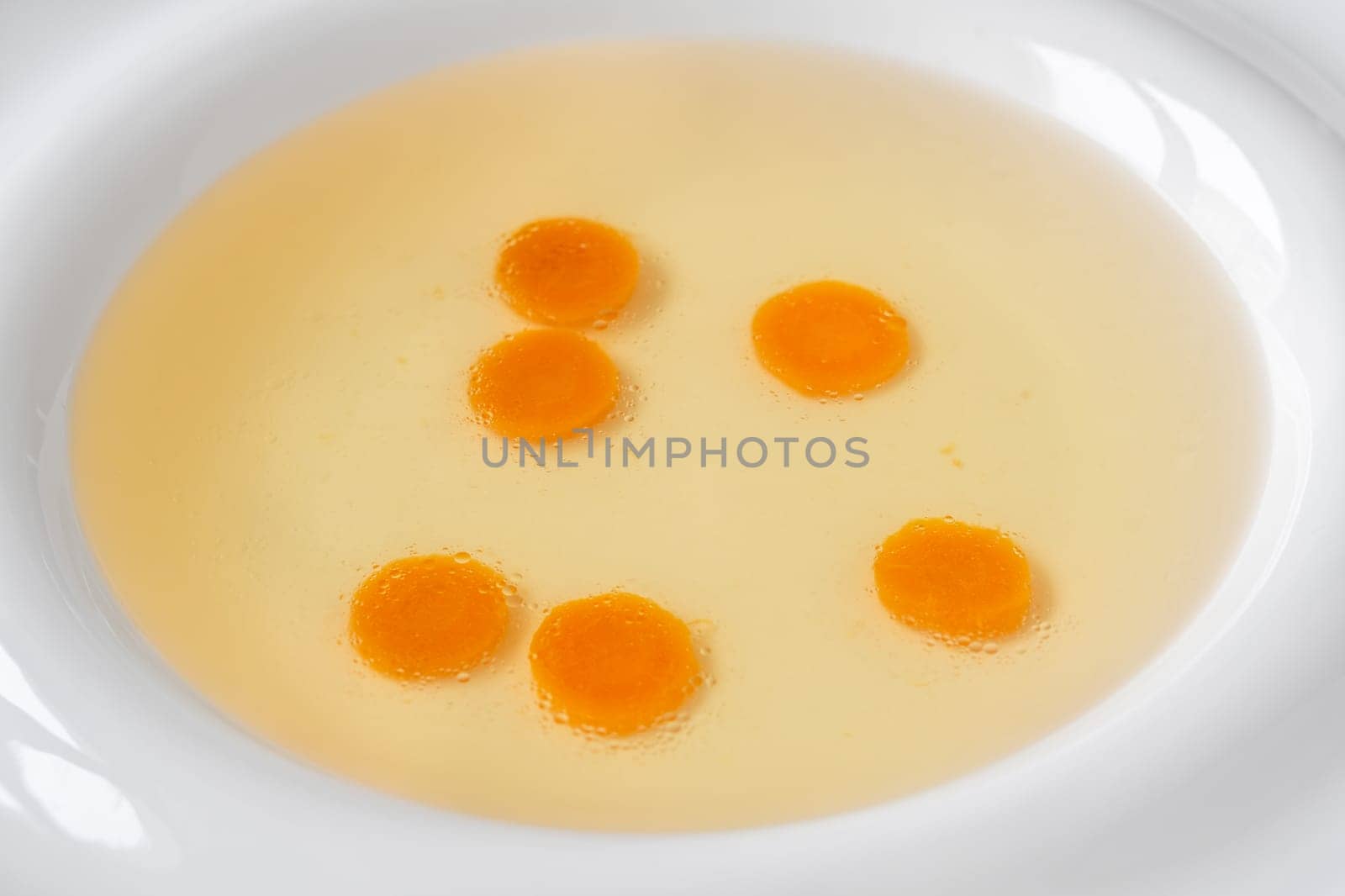 Portion of clear chicken broth in white plate