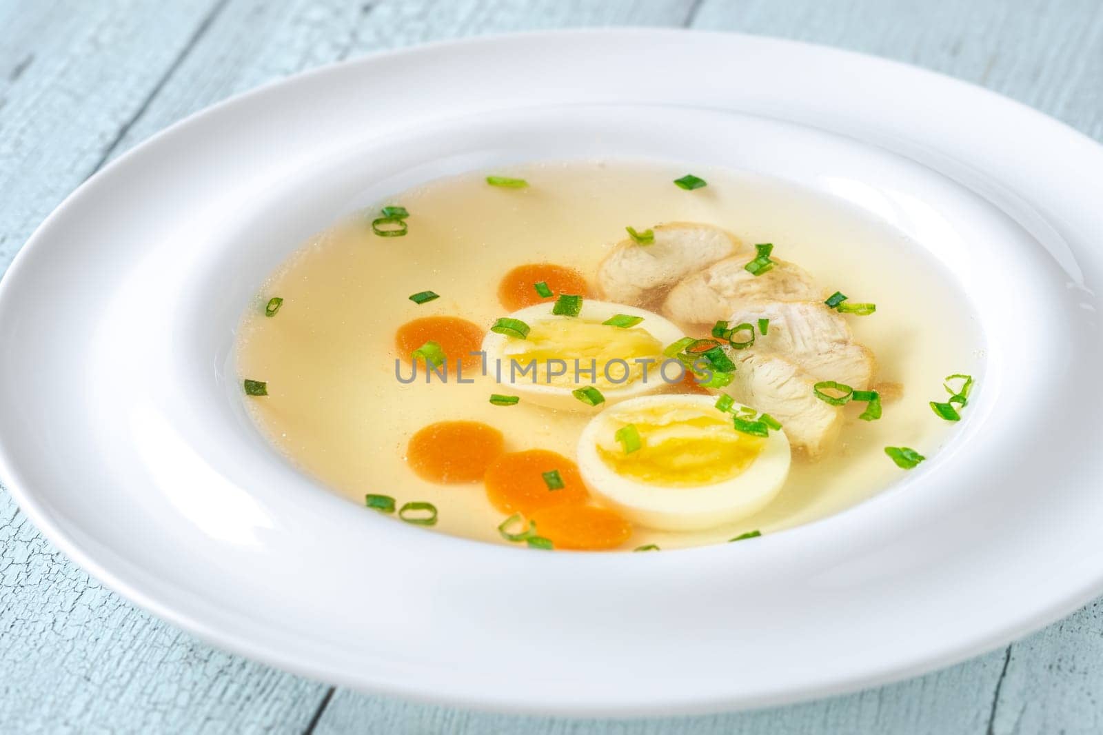 Portion of clear chicken broth in white plate