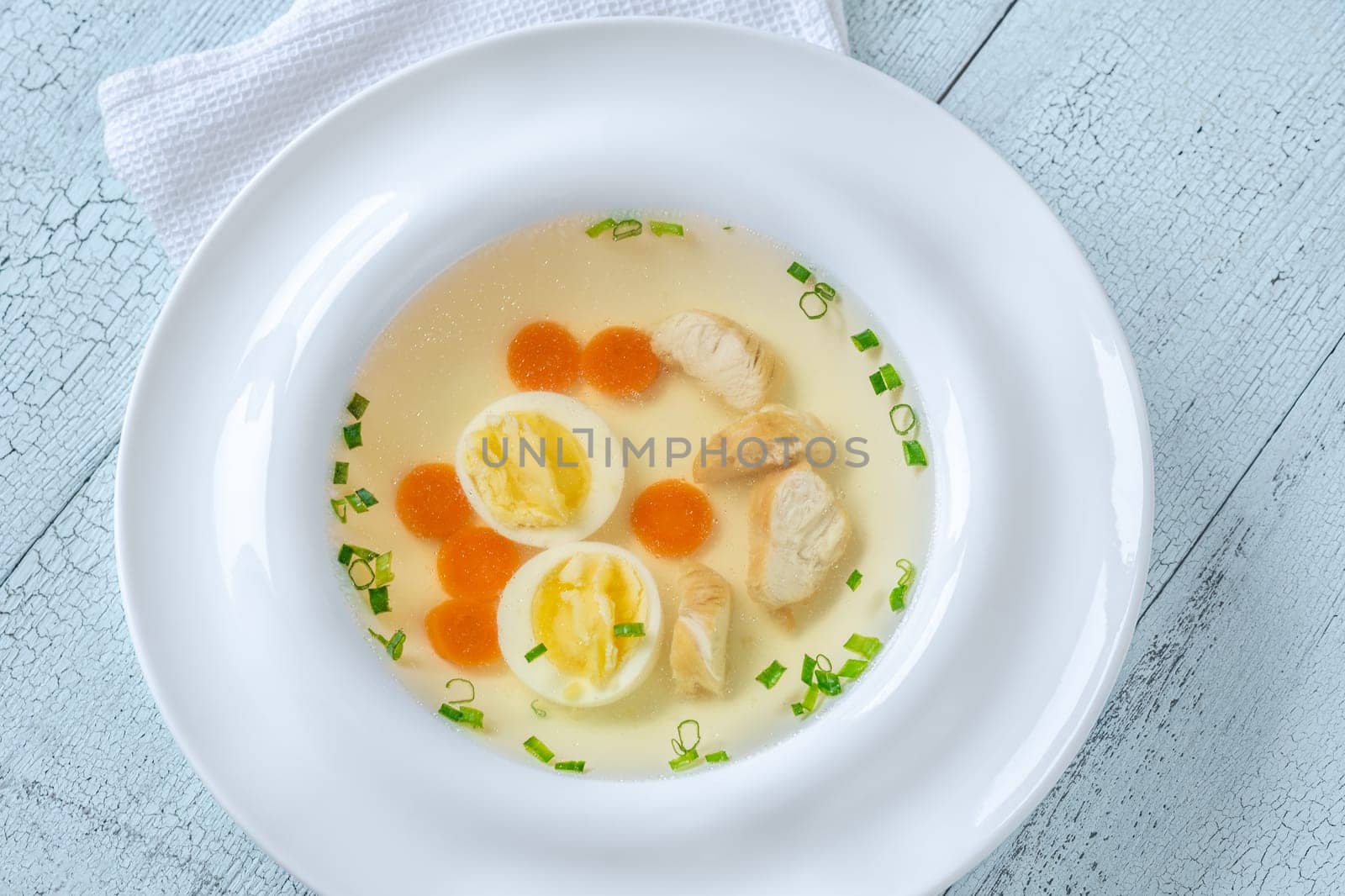 Portion of clear chicken broth in white plate