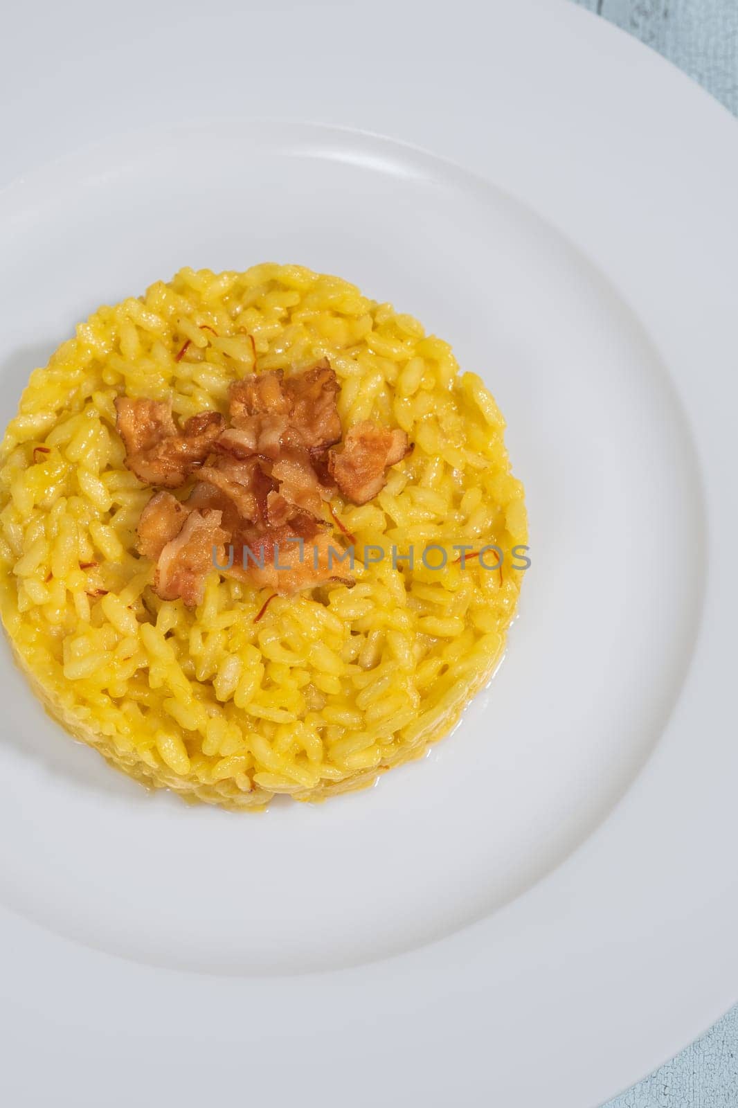Portion of saffron risotto garnished with pancetta