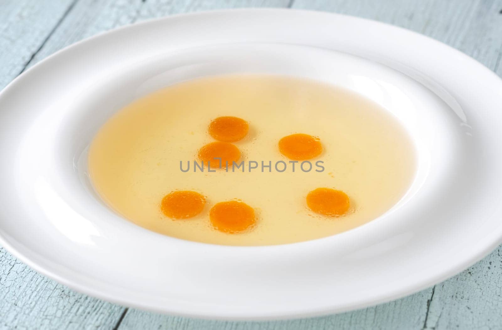 Portion of clear chicken broth in white plate