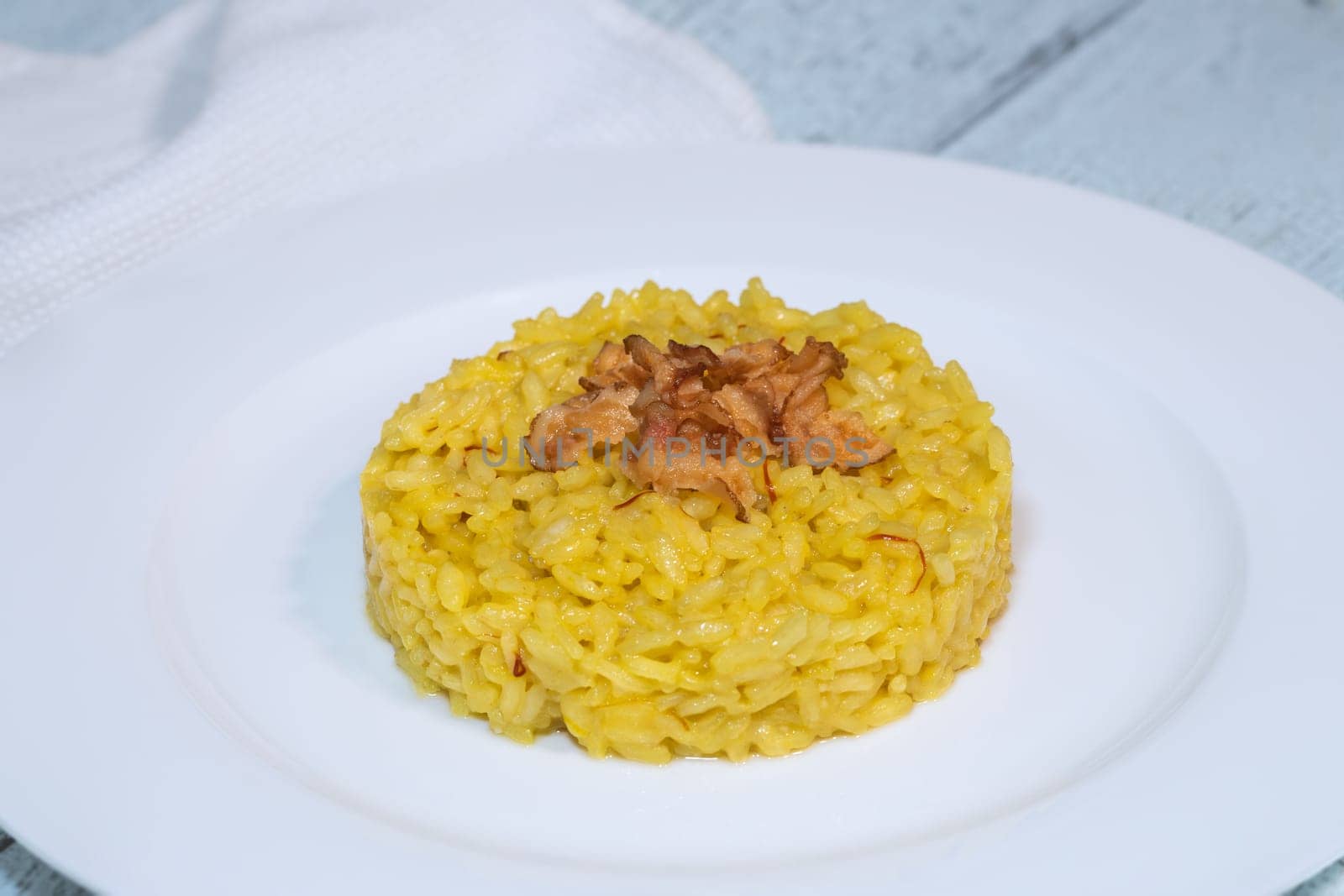 Portion of saffron risotto garnished with pancetta