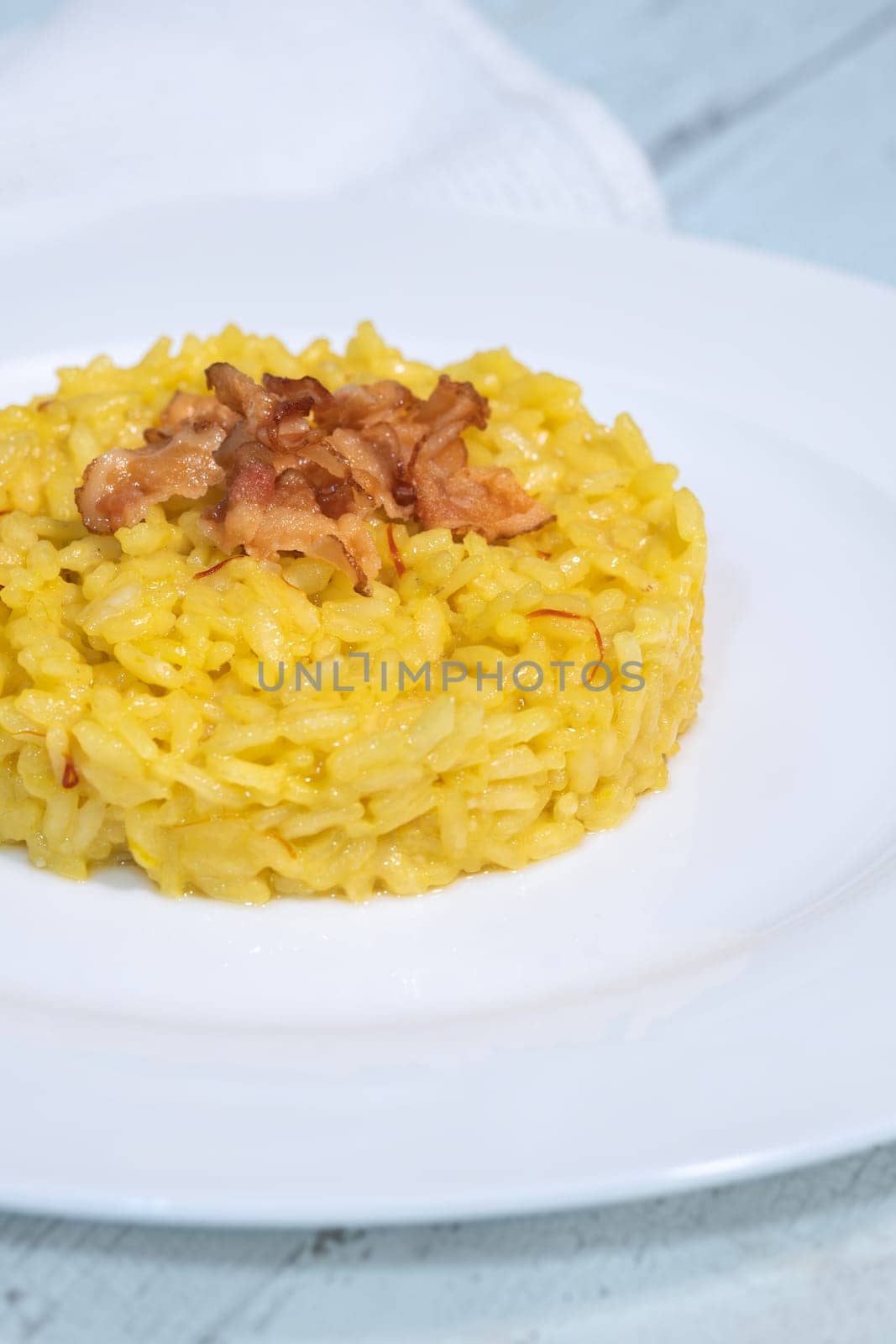Portion of saffron risotto garnished with pancetta