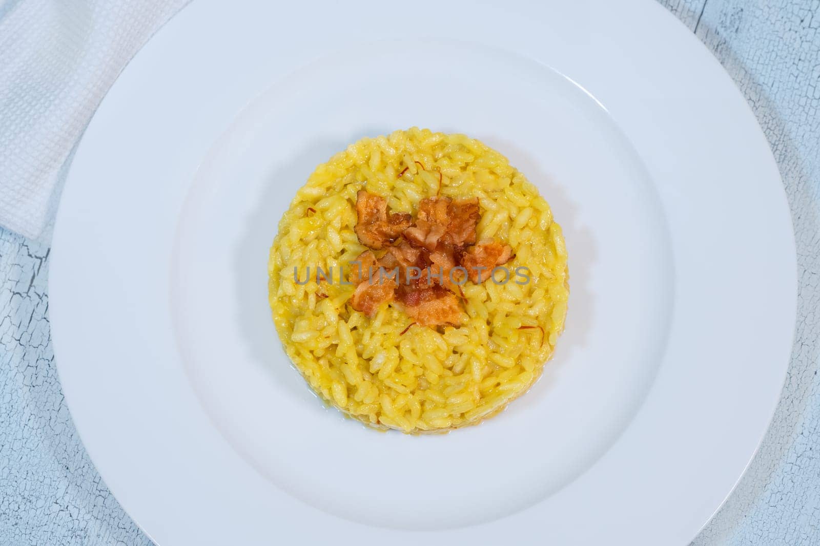 Portion of saffron risotto garnished with pancetta