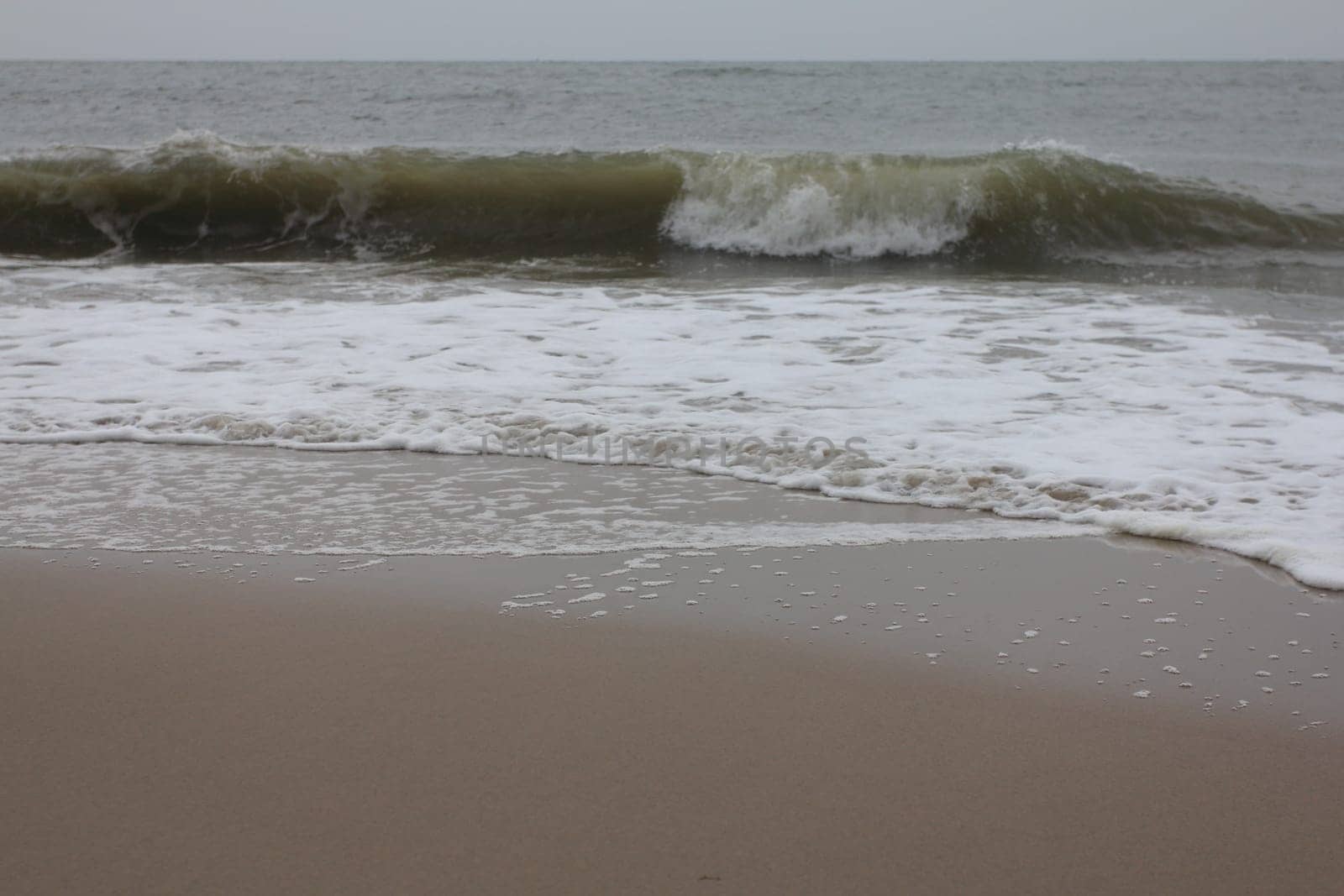Waves with white crests inundate the sandy beach