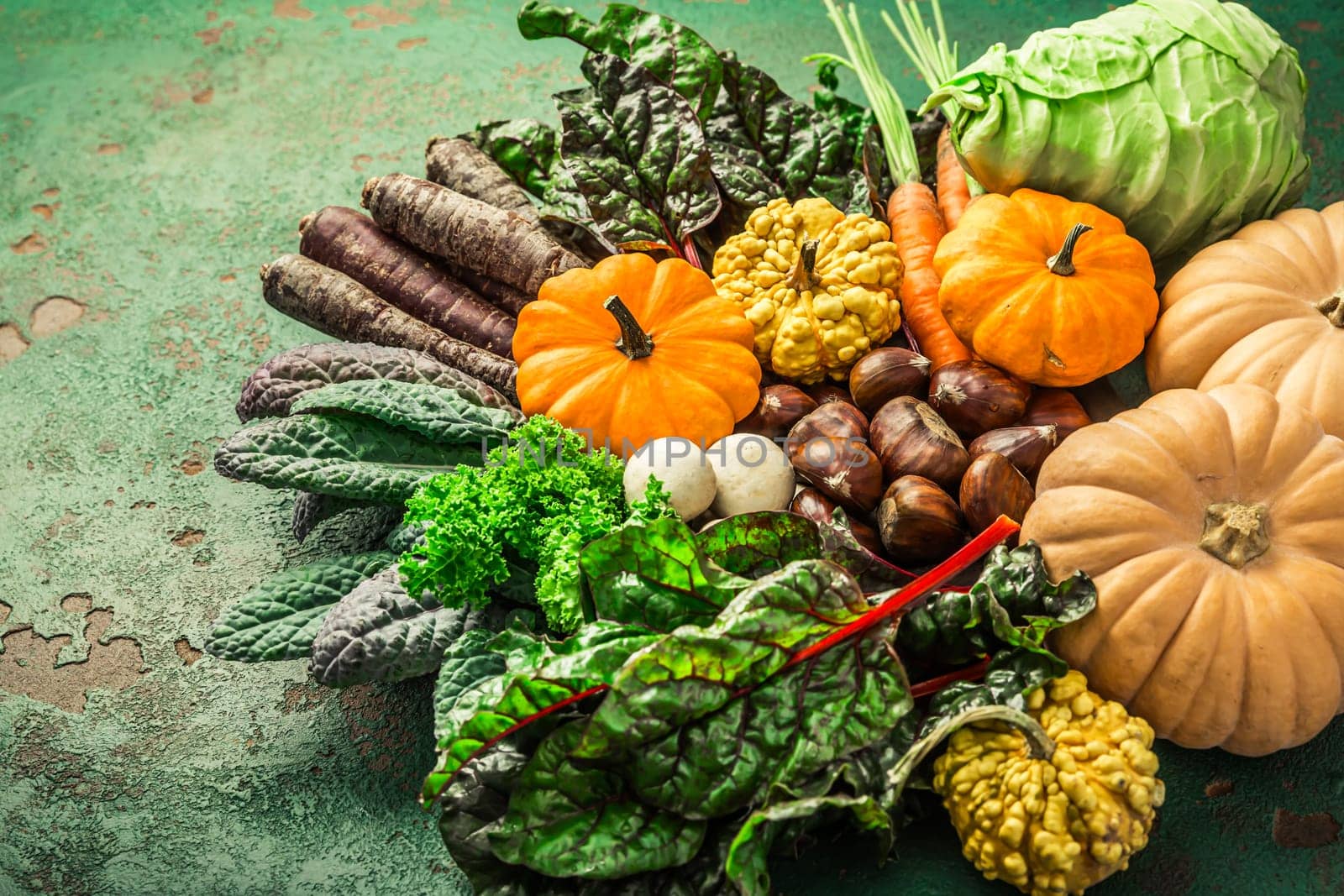Organic raw autumn and winter vegetables on kitchen table with carrots, chesnuts, chard, kale