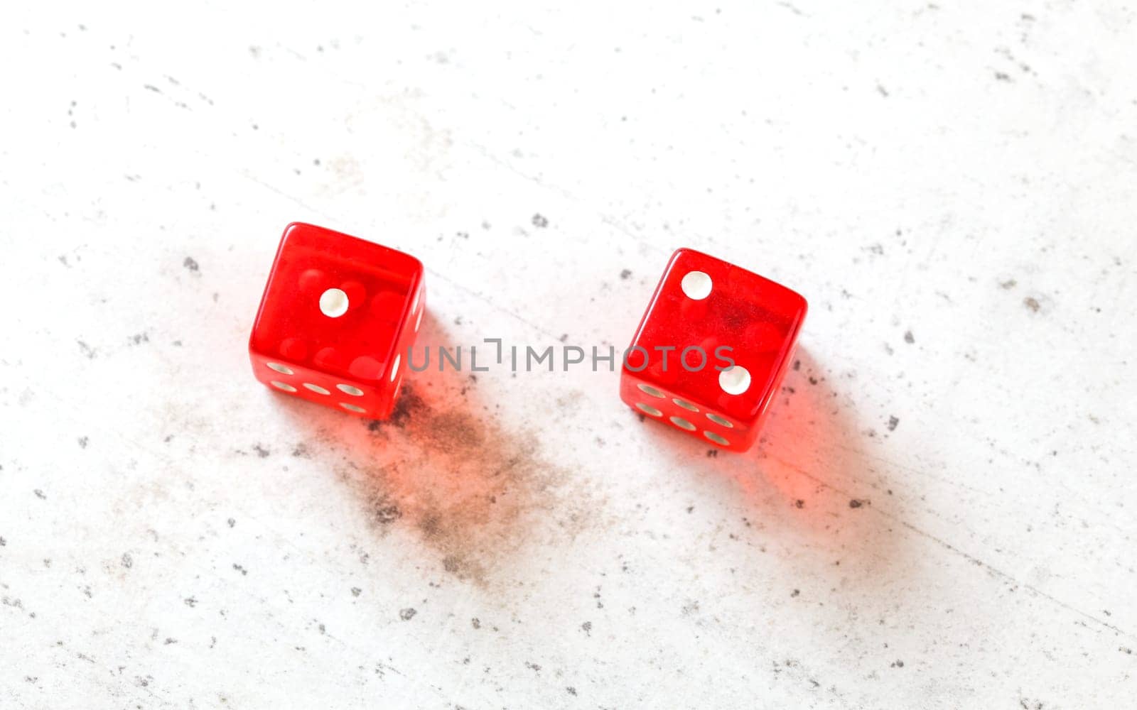 Two red craps dices showing Ace Deuce (Number 1 and 2) overhead shot on white board