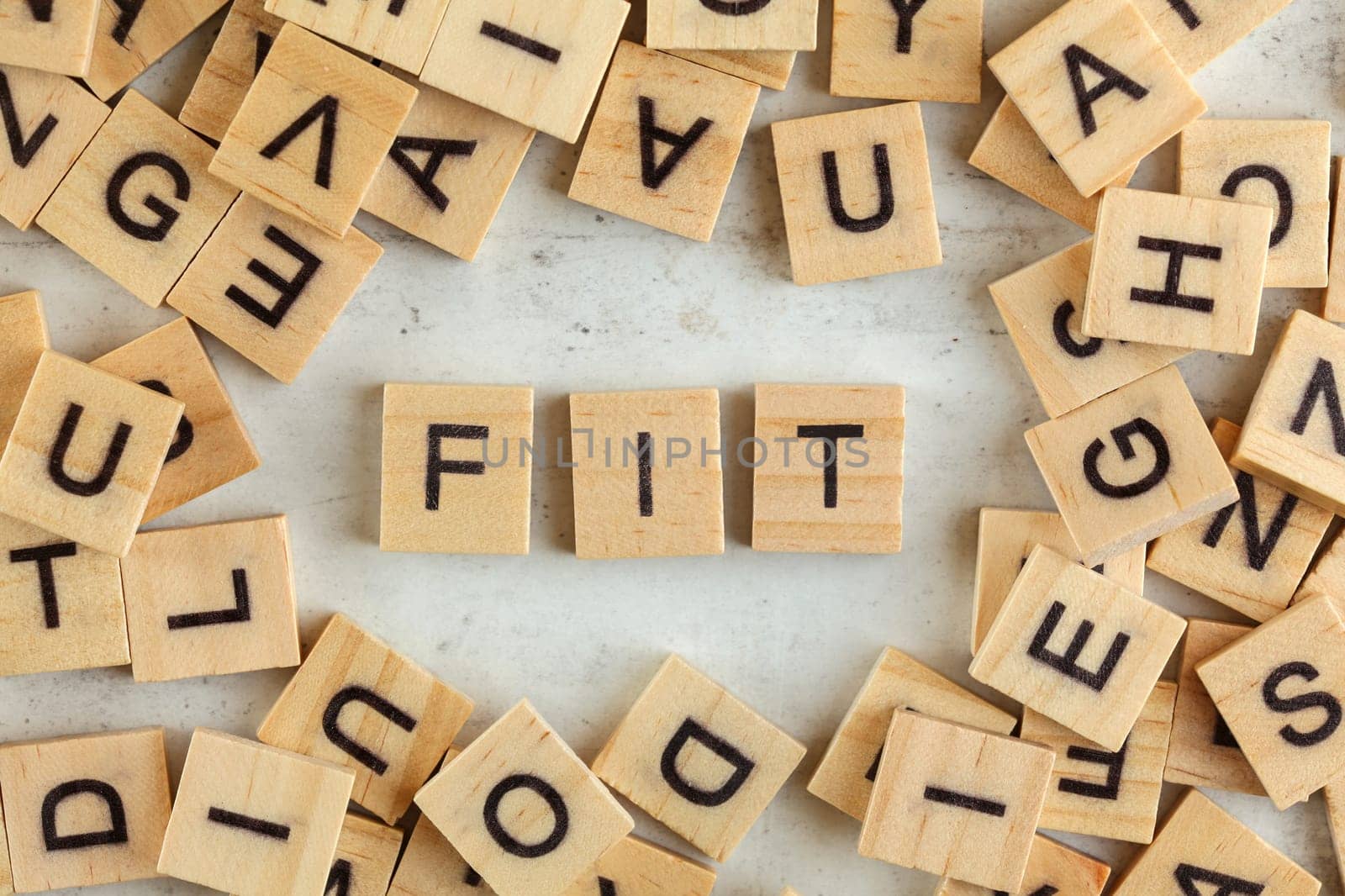 Top down view, pile of square wooden blocks with word FIT on white board.