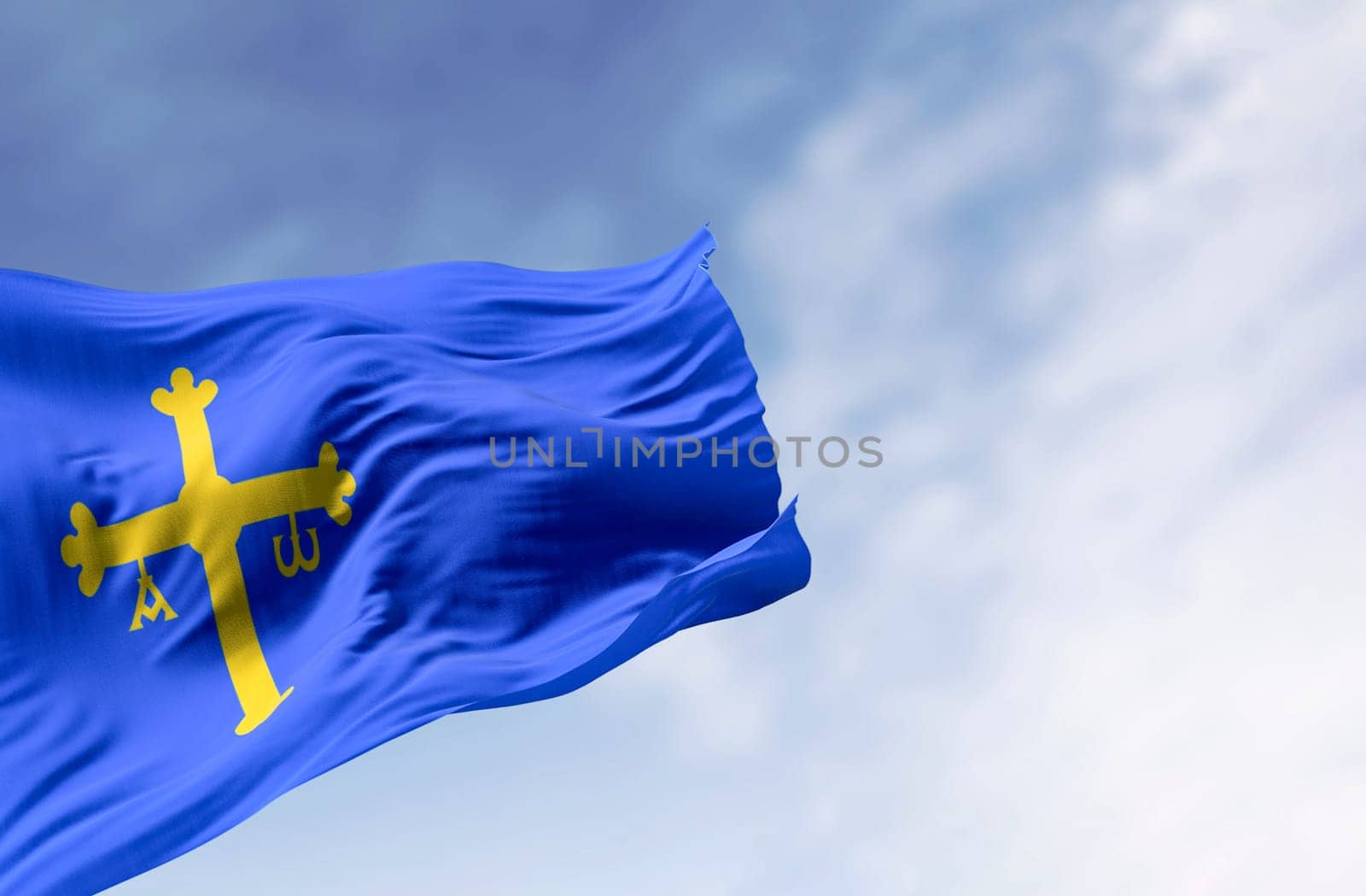 The Asturias flag waving in the wind on a clear day. Autonomous community in northern Spain. Blue with golden victory cross shifted towards the hoist side. 3d illustration render. Rippling fabric