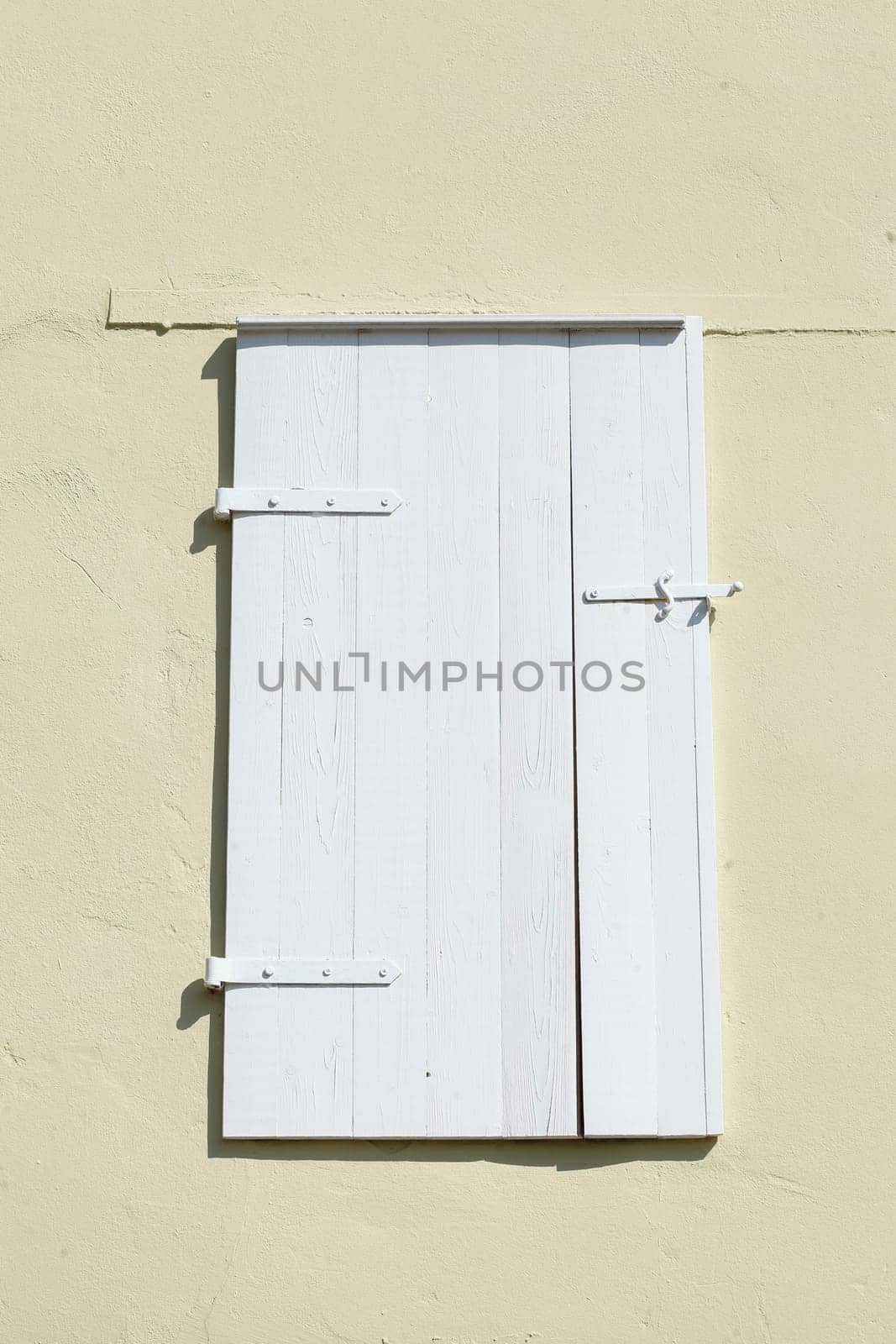 Old white shutter and window made of wood on a light house wall, Germany