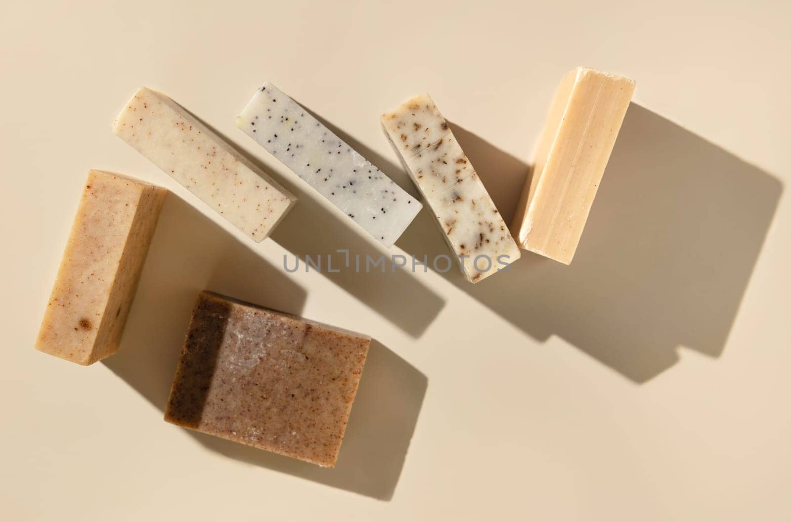 Natural herbal beige and brown handmade soap bars on light beige top view, hard shadows. Hygiene products for Spa and skin care. Using organic handmade sopas in everyday routine