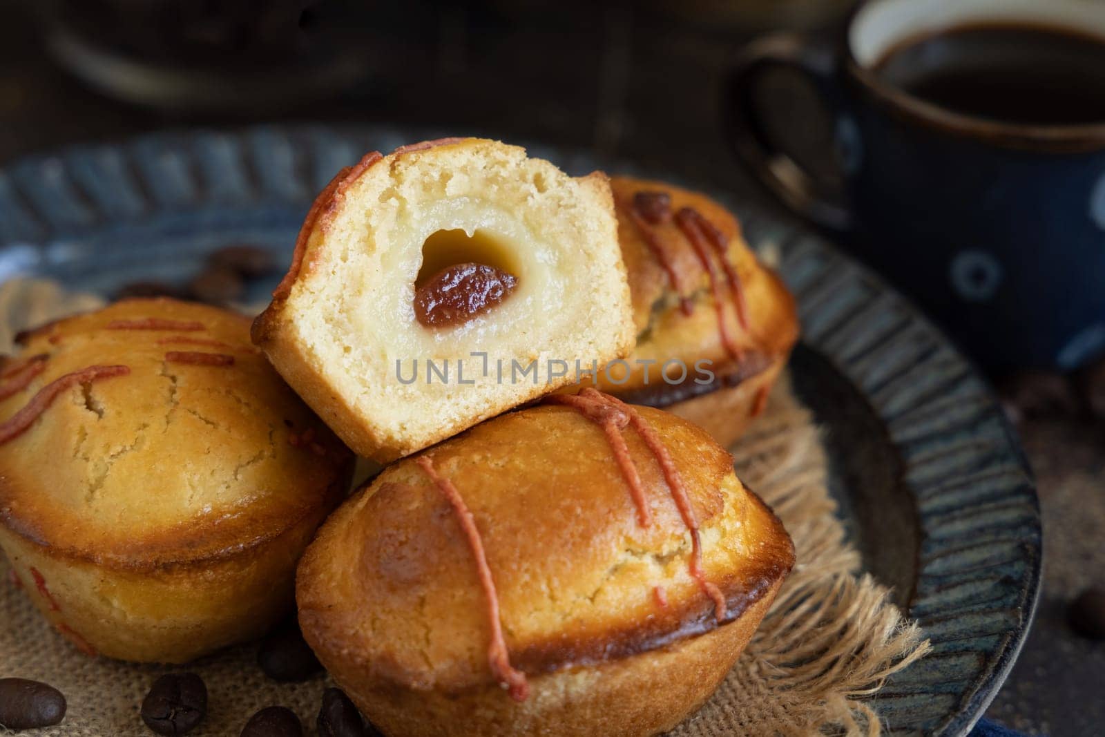 Pasticciotto leccese pastries on a dark blue plate near coffe cup on dark table, typical apulian breakfast, close up. Table decorated with coffee beans