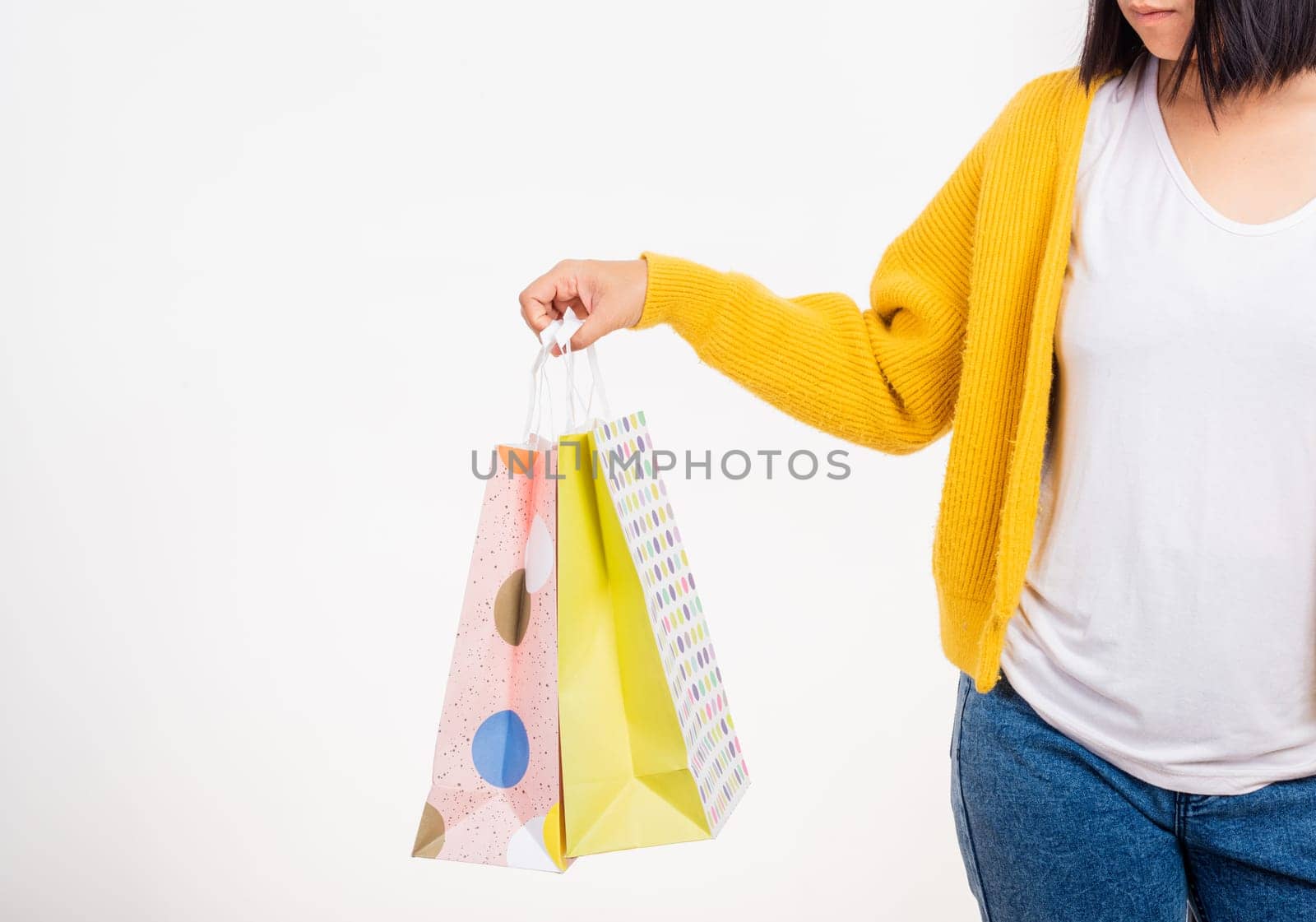 Happy young female hold many packets within arms, woman hand she wears a yellow shirt holding shopping bags multicolor isolated on white background, Black Friday sale concept