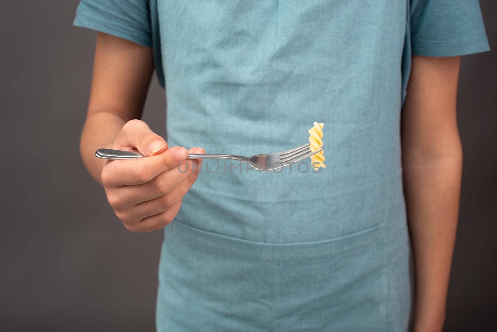 Cooked fusilli pasta on a fork, italian food ingredients, preparing dinner