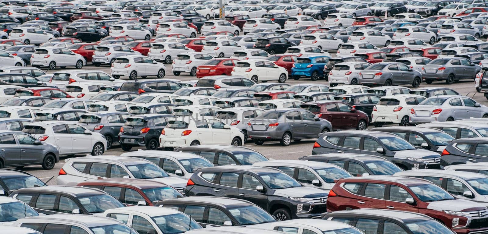 Lamchabang, Thailand - July 02, 2023 A distribution center in a sunny car factory houses rows of new cars. A top view reveals a bustling parking lota symbol of modern manufacturing and technology.