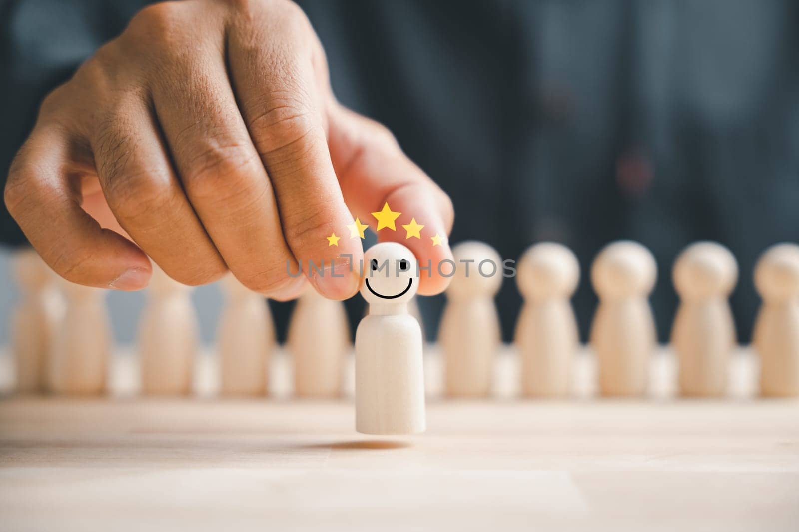 Wooden human figure firmly clutched by man hand. HR officer looks for leader and CEO. Leader steps out of the crowd. Personal development, motivation, challenge. HR, HRM, HRD concepts.