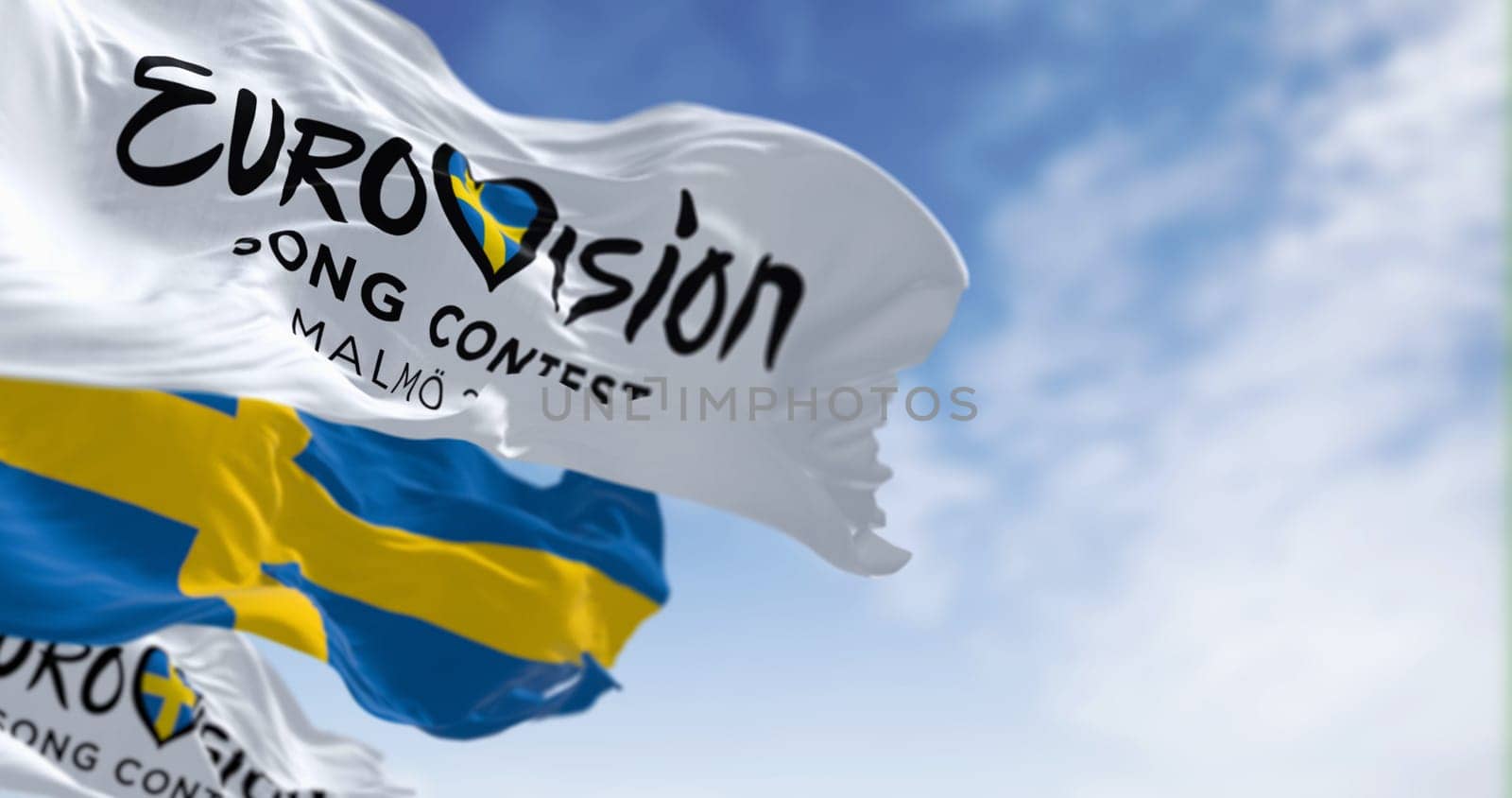 Malmö, SE, Oct. 25 2023: Eurovision Song Contest 2024 and swedish flags waving on a clear day. The 2024 edition will take place in Malmö on may. Illustrative editorial 3d illustration render