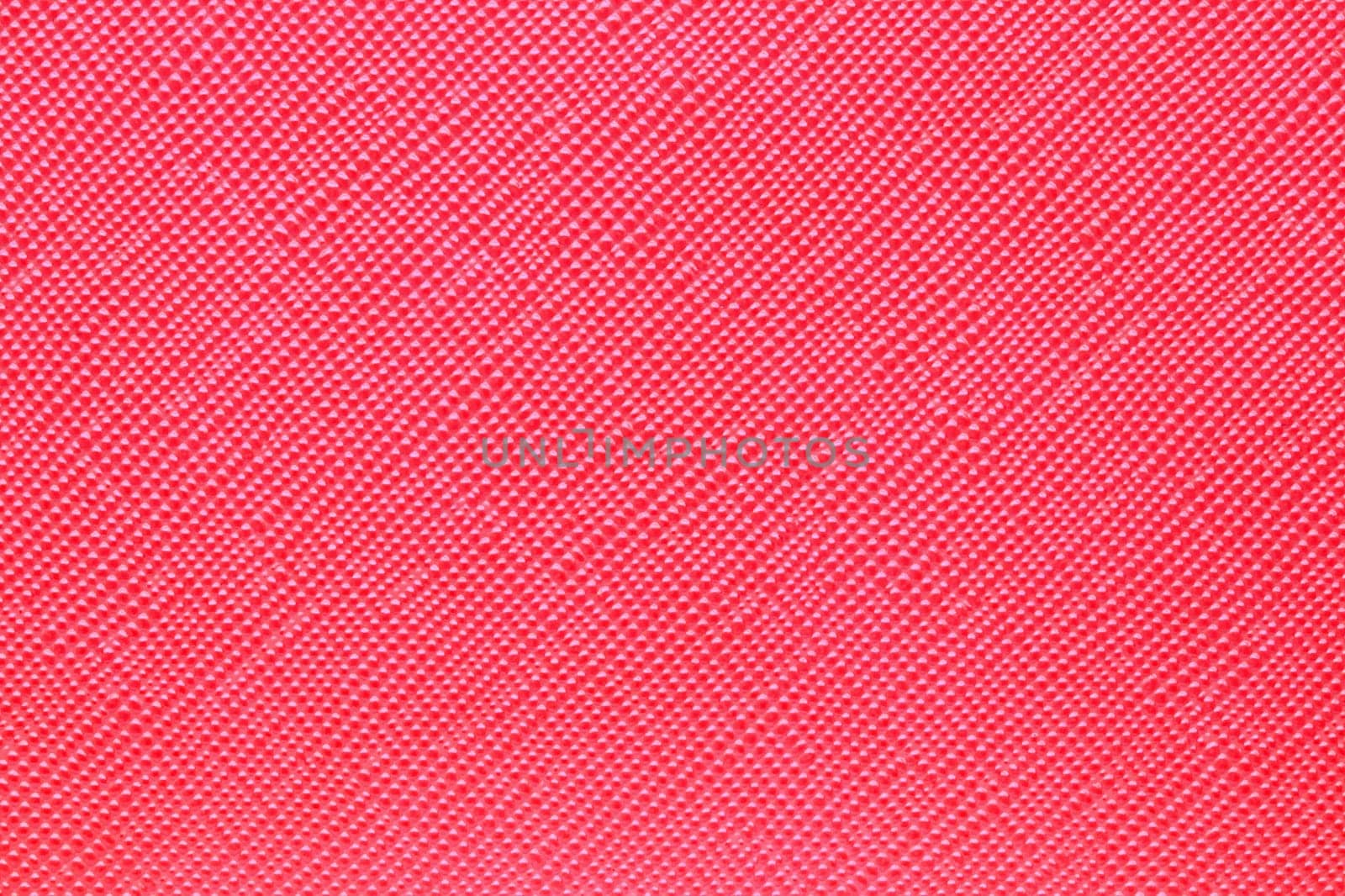 Seamless plastic texture background. Close-up of a detail from a red surface of a cosmetic bag. Beautiful backdrop. Macro.