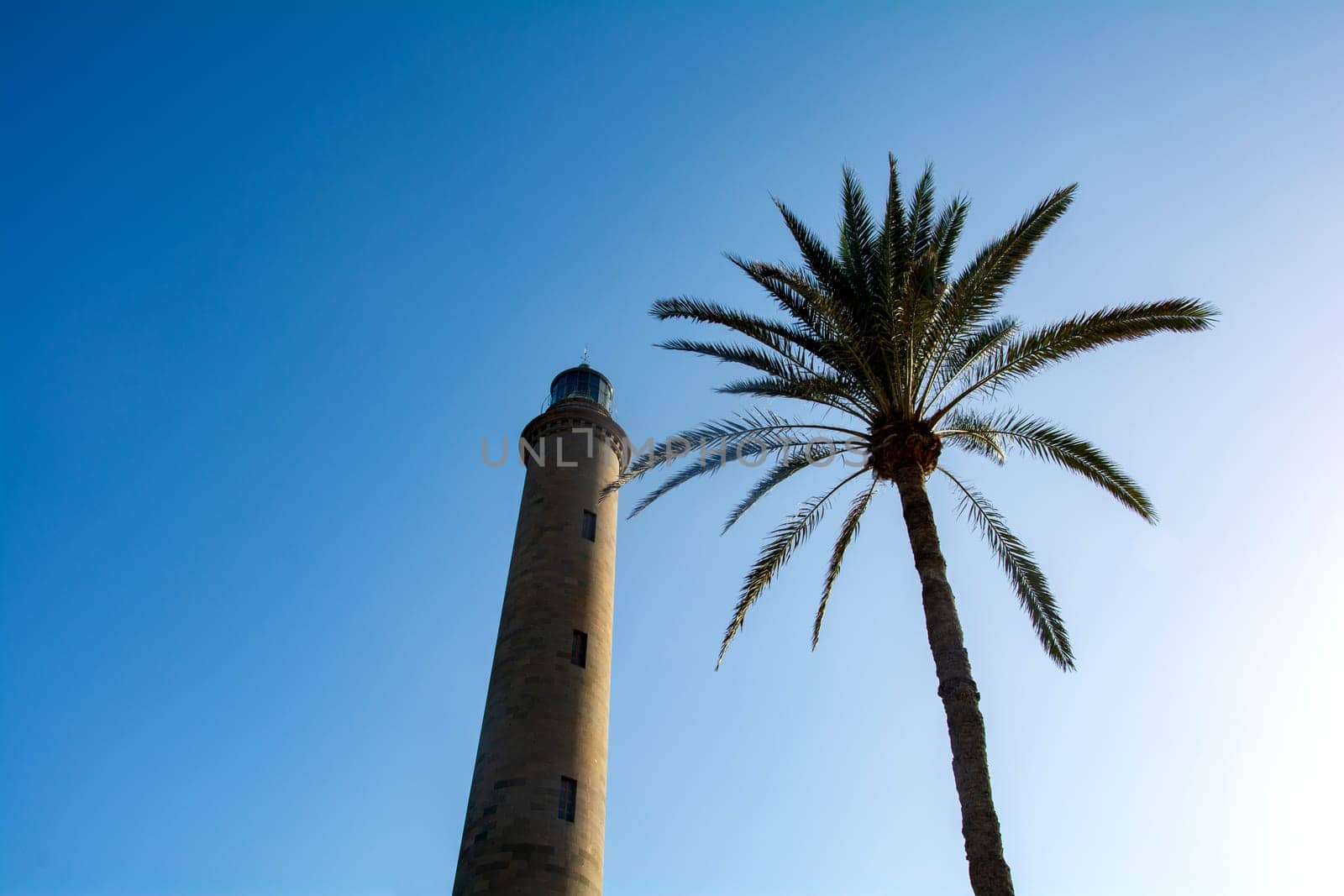 Lighthouse in Maspalomas ( Faro de Maspalomas ) on the Canary Island of Gran Canaria in Spain with palm tree