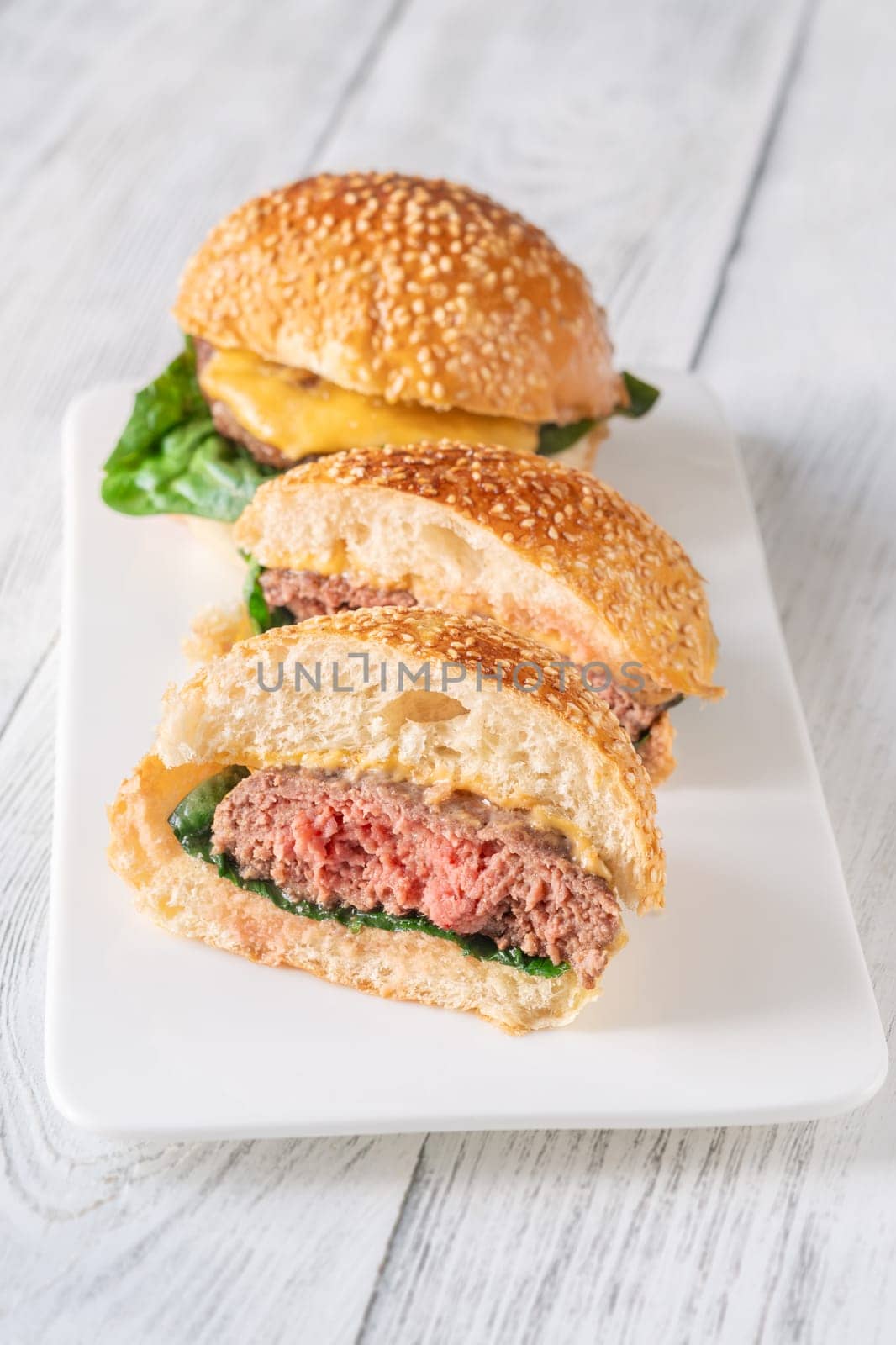 Two homemade cheeseburges on the wooden background