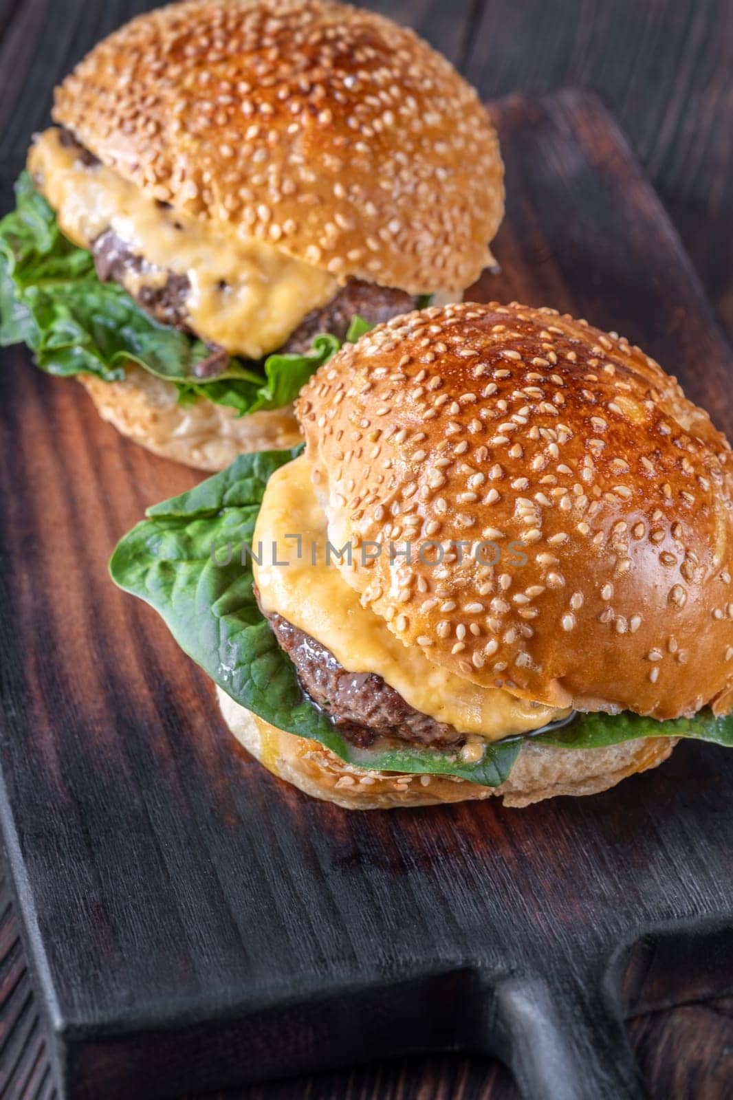 Two homemade cheeseburges on the wooden background