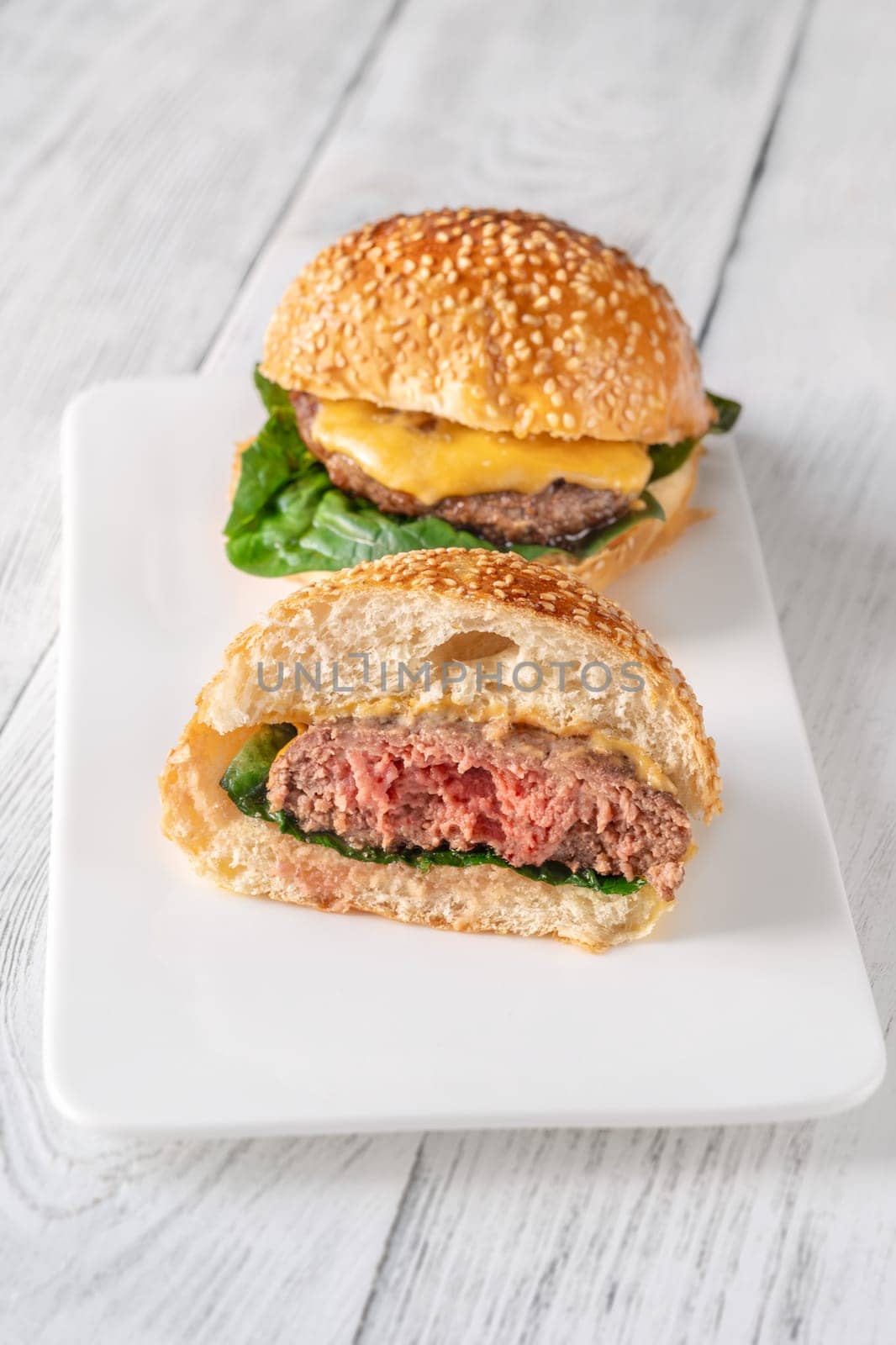Two homemade cheeseburges on the wooden background