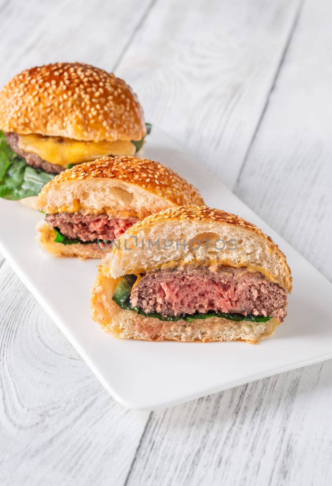 Two homemade cheeseburges on the wooden background
