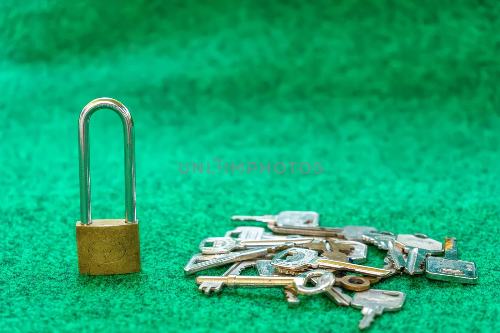 Brass Padlock and many types of keys on green carpet background.