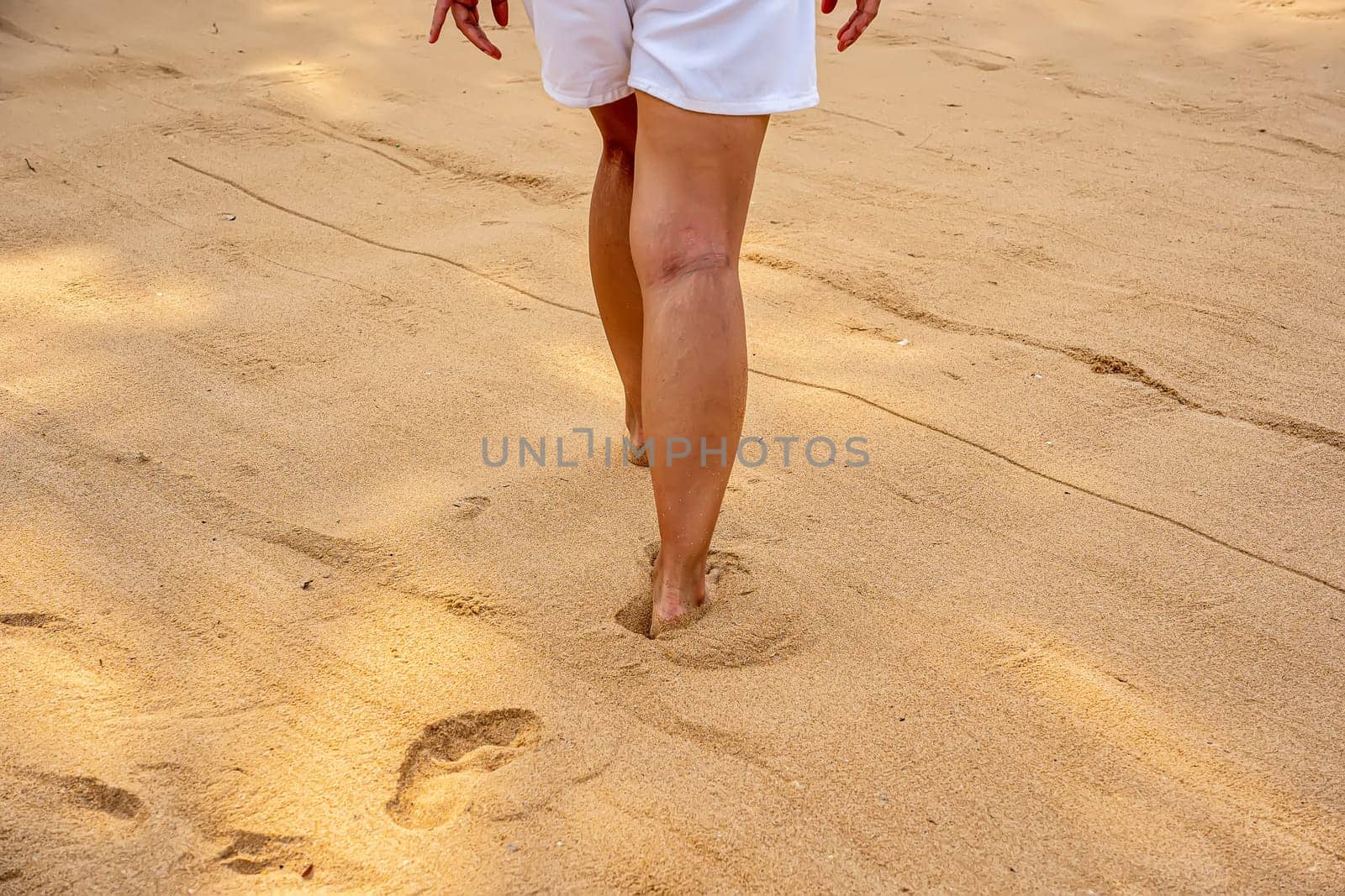 Woman walking on the sand at the beach.